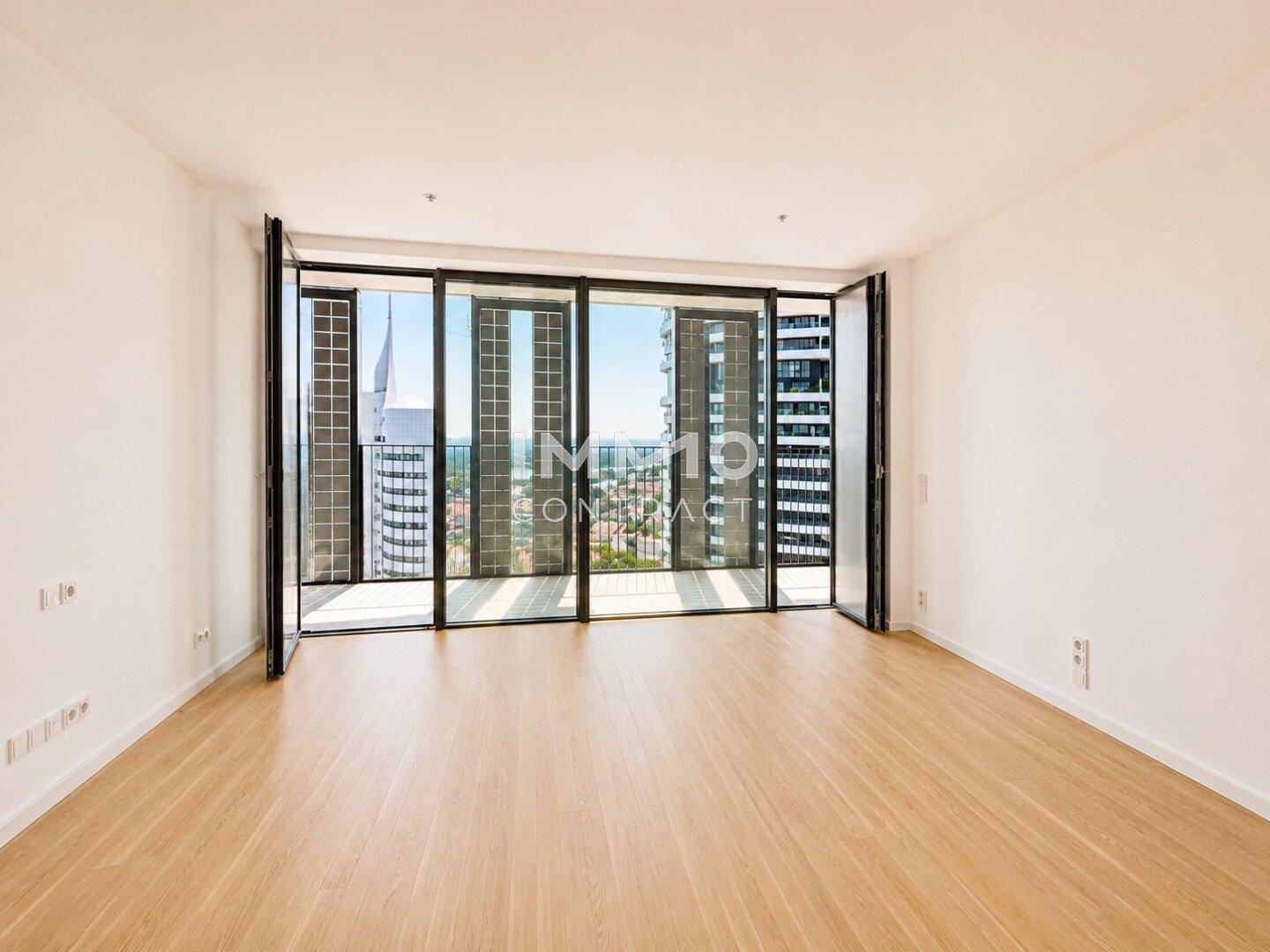 Geräumiger Wohnraum mit großen Fenstern, die einen weiten Blick auf die Stadt bieten.