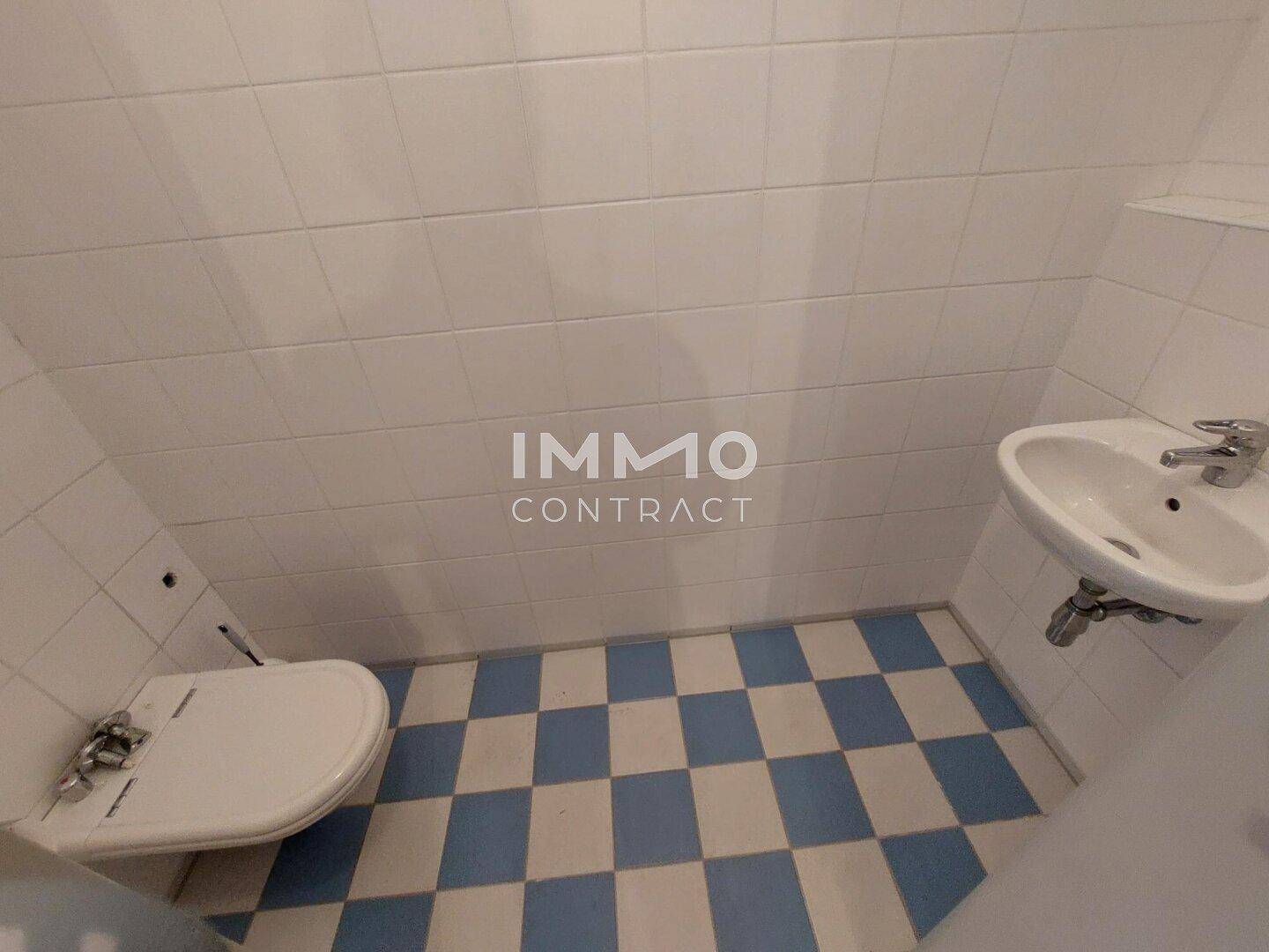 Kleines Gäste-WC mit blau-weiß karierten Bodenfliesen und weiß gefliesten Wänden.
