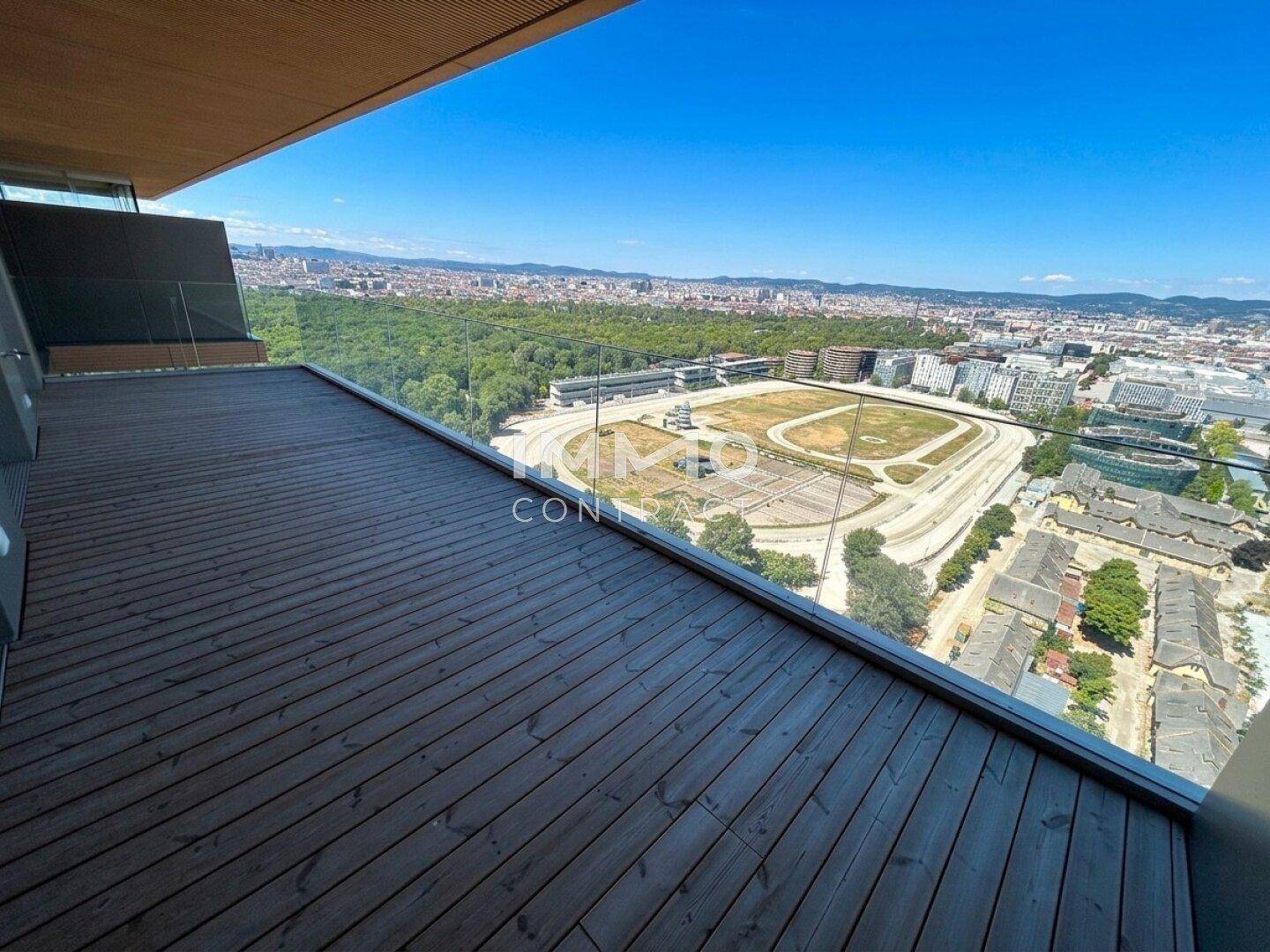 Große, unmöblierte Terrasse mit Holzboden und weitem Blick über die Stadt und Rennbahn.