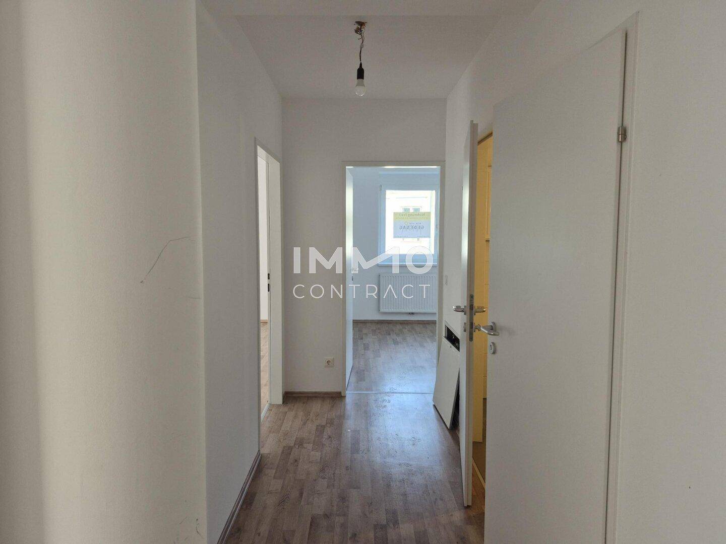 Langer, heller Flur mit Laminatboden, der zu weiteren Zimmern der Wohnung führt.