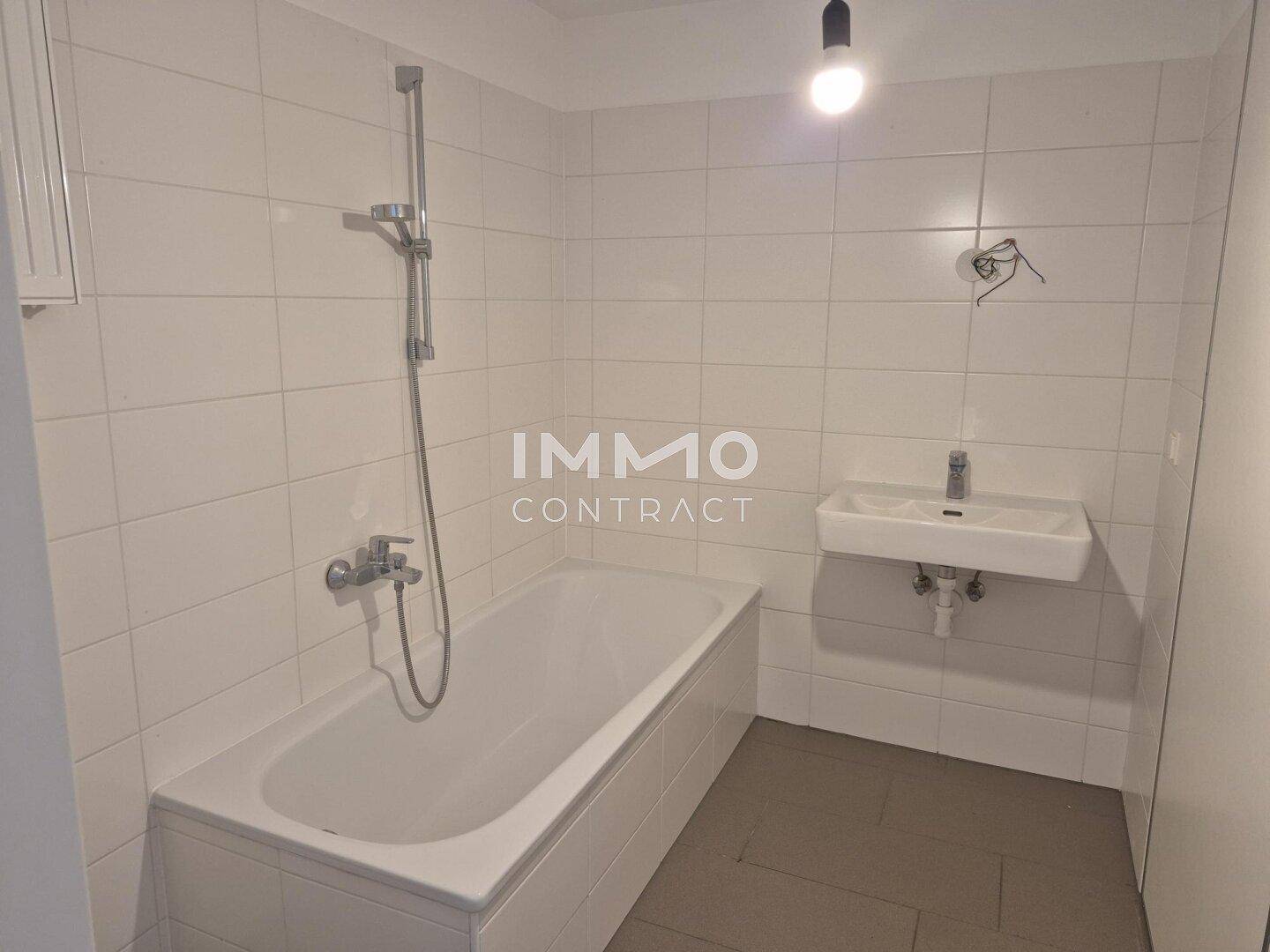 Badezimmer mit Badewanne, Waschbecken und weißen Fliesen an den Wänden.