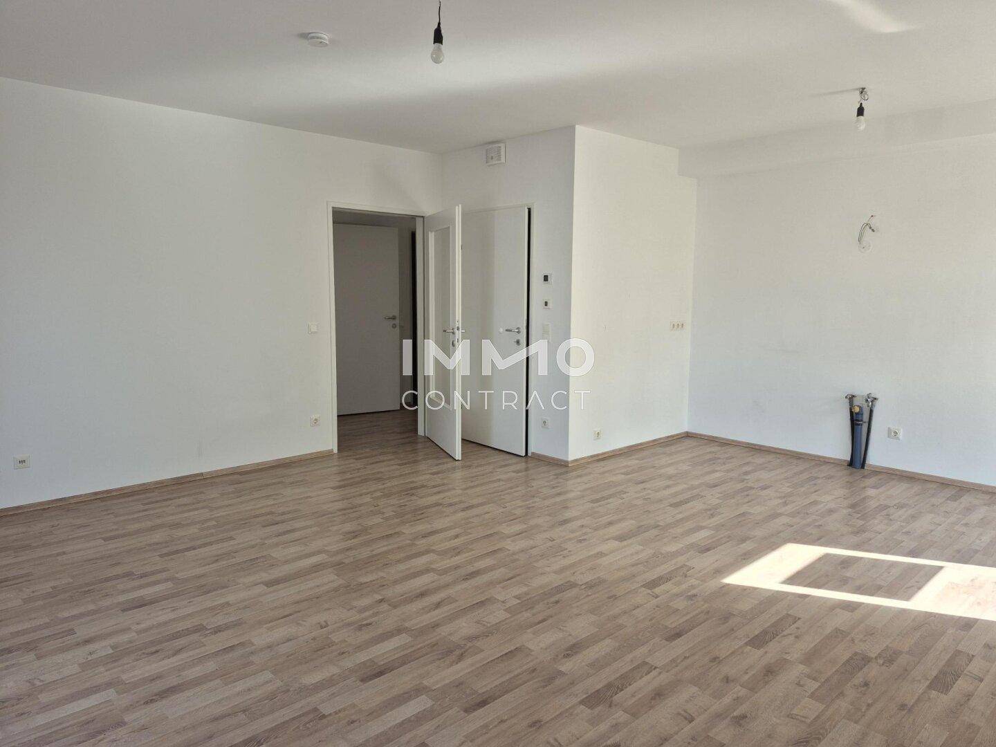 Geräumiges Wohnzimmer mit Laminatboden und viel Tageslicht, bereit zur individuellen Gestaltung.