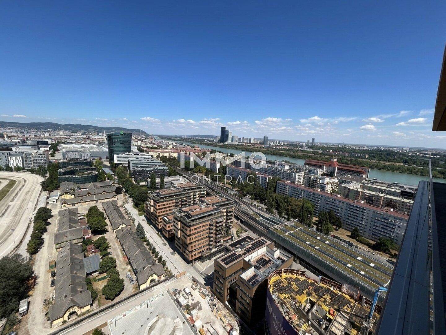 Panoramablick über die Stadt, die Donau und moderne Gebäude unter blauem Himmel.