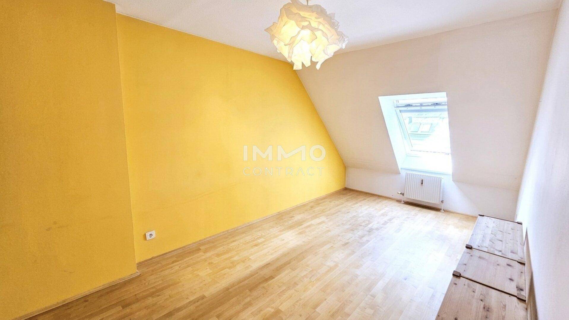 Helles Zimmer im Dachgeschoss mit gelber Wand und Holzboden, bereit zur Einrichtung.
