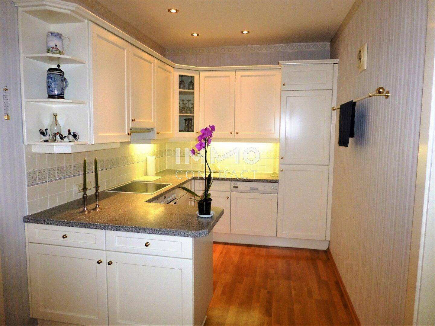 Helle Einbauküche mit weißen Schränken, Granitarbeitsplatte und Holzboden in modernem Design.