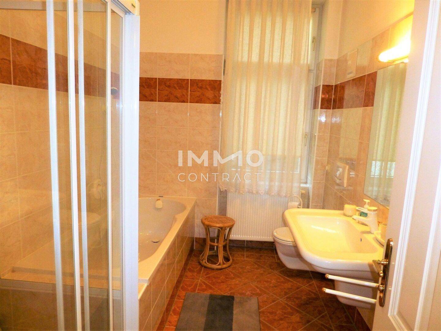 Badezimmer mit Duschkabine, Badewanne, WC und Waschbecken, gefliest in Braun- und Beigetönen.