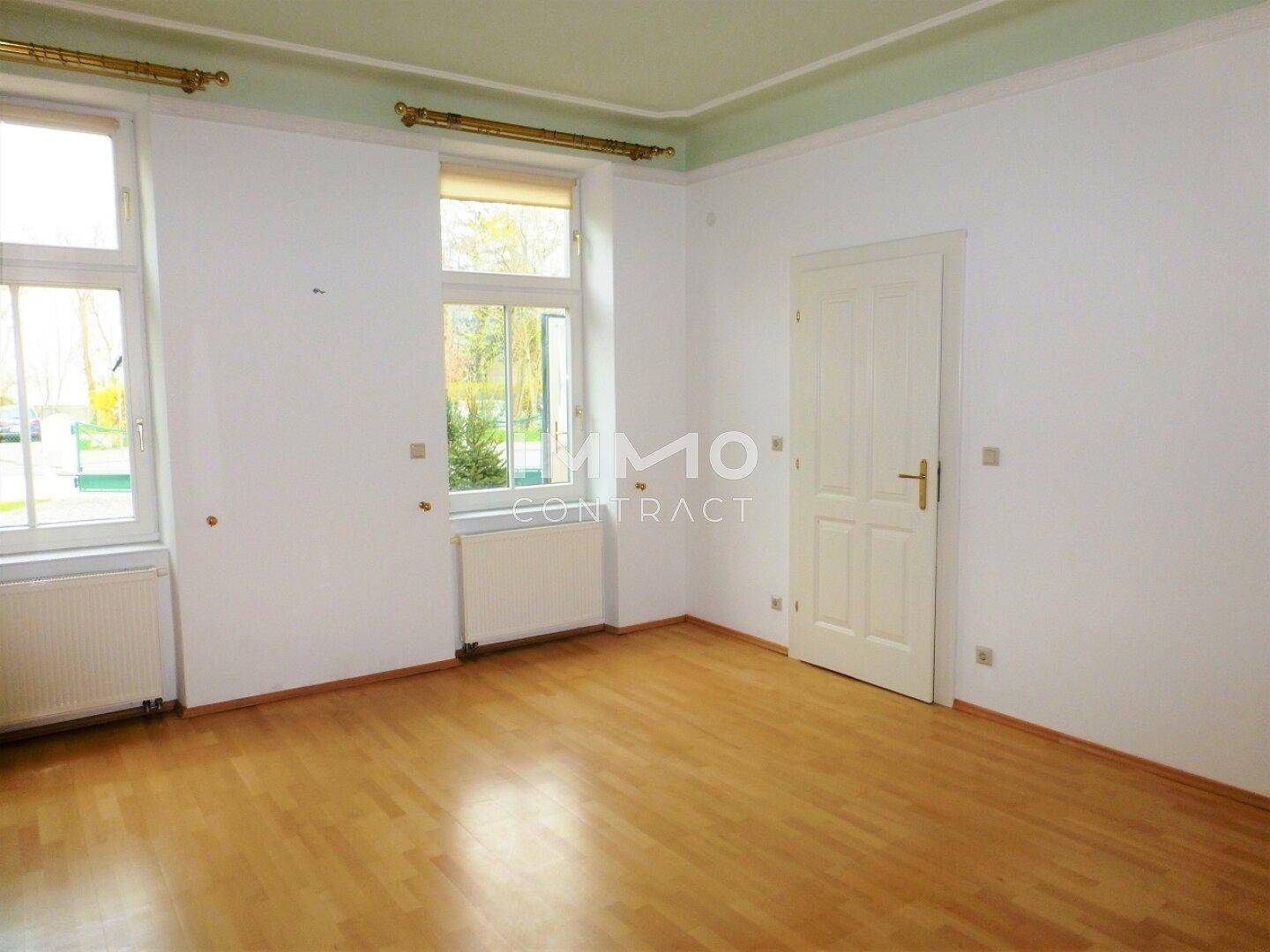 Helles Zimmer mit Holzboden, weißen Wänden und einer klassischen Tür.