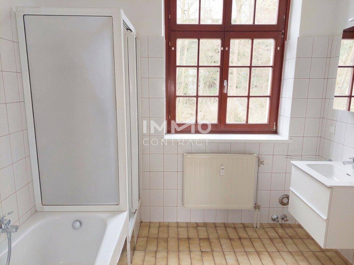Badezimmer mit Badewanne, Duschabtrennung, Waschbecken und einem Fenster.