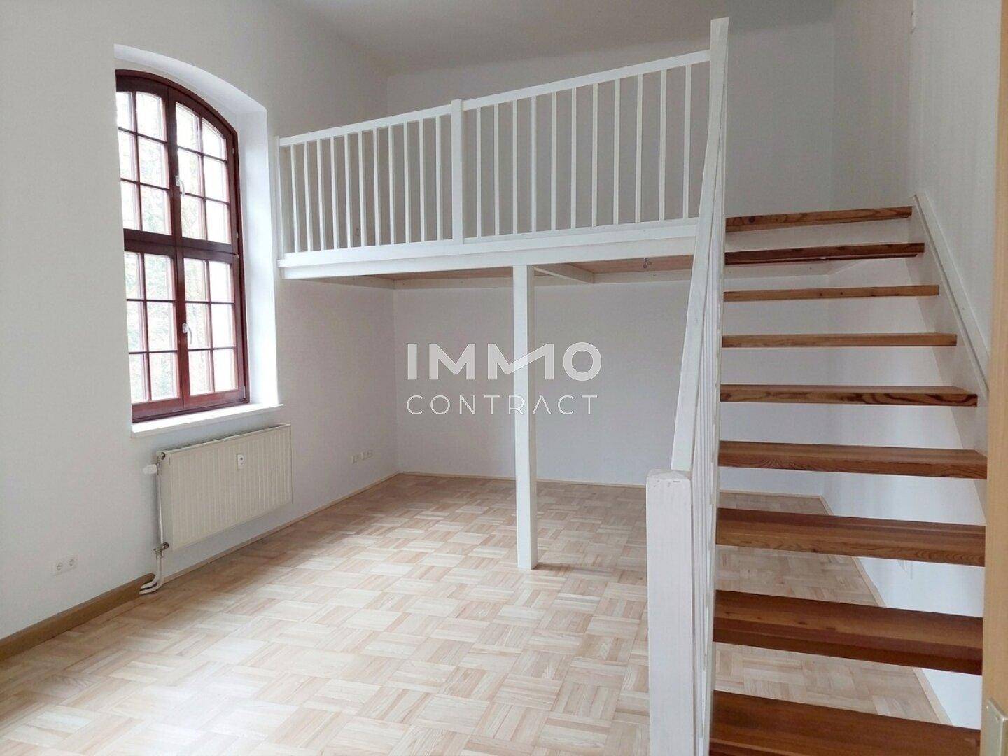 Wohnbereich mit Galerie, Holztreppe und Parkettboden, hell durch große Fenster.