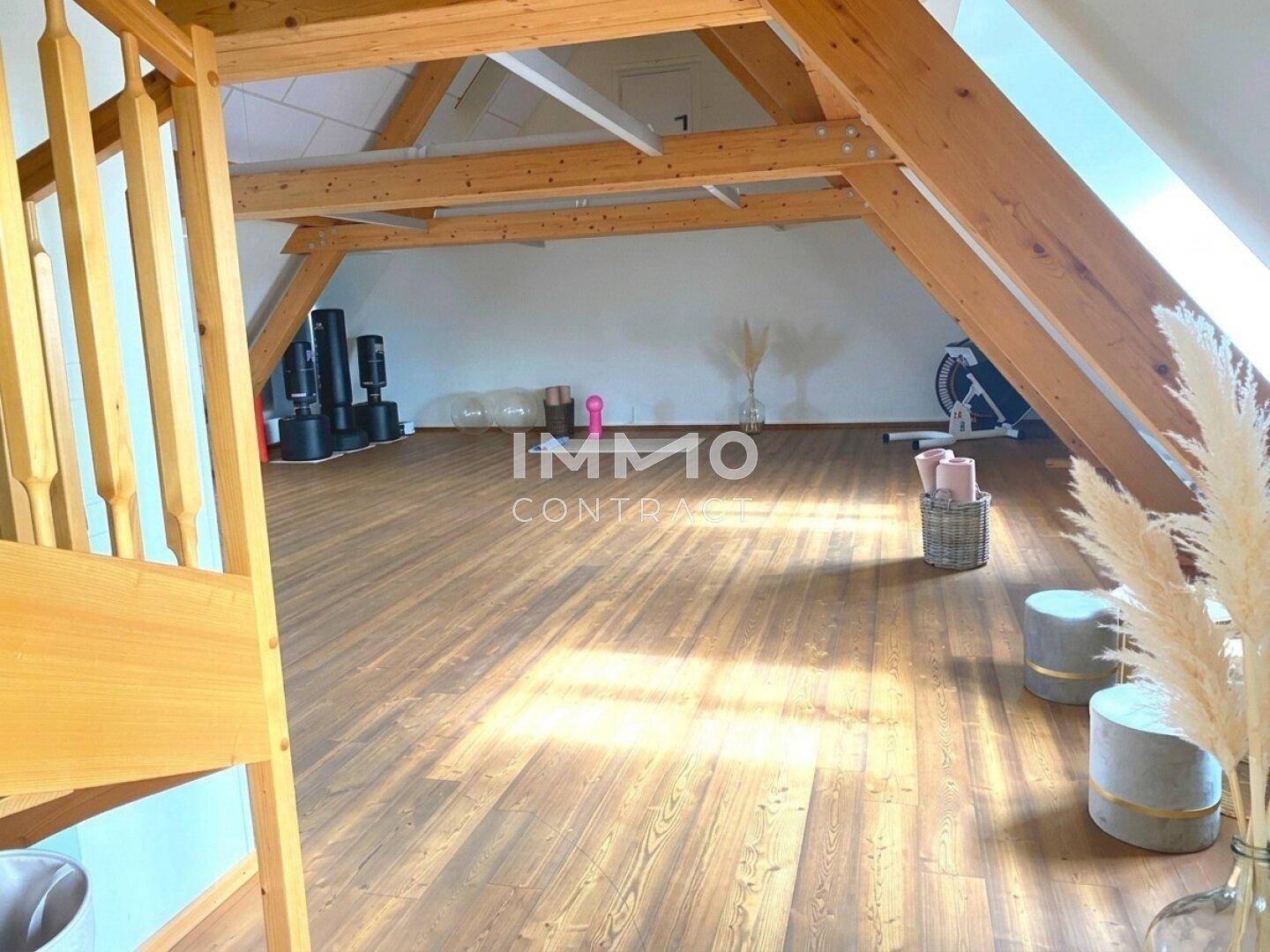 Geräumiger Mehrzweckraum mit Holzboden und sichtbaren Dachbalken, ideal für Sport oder Hobby.