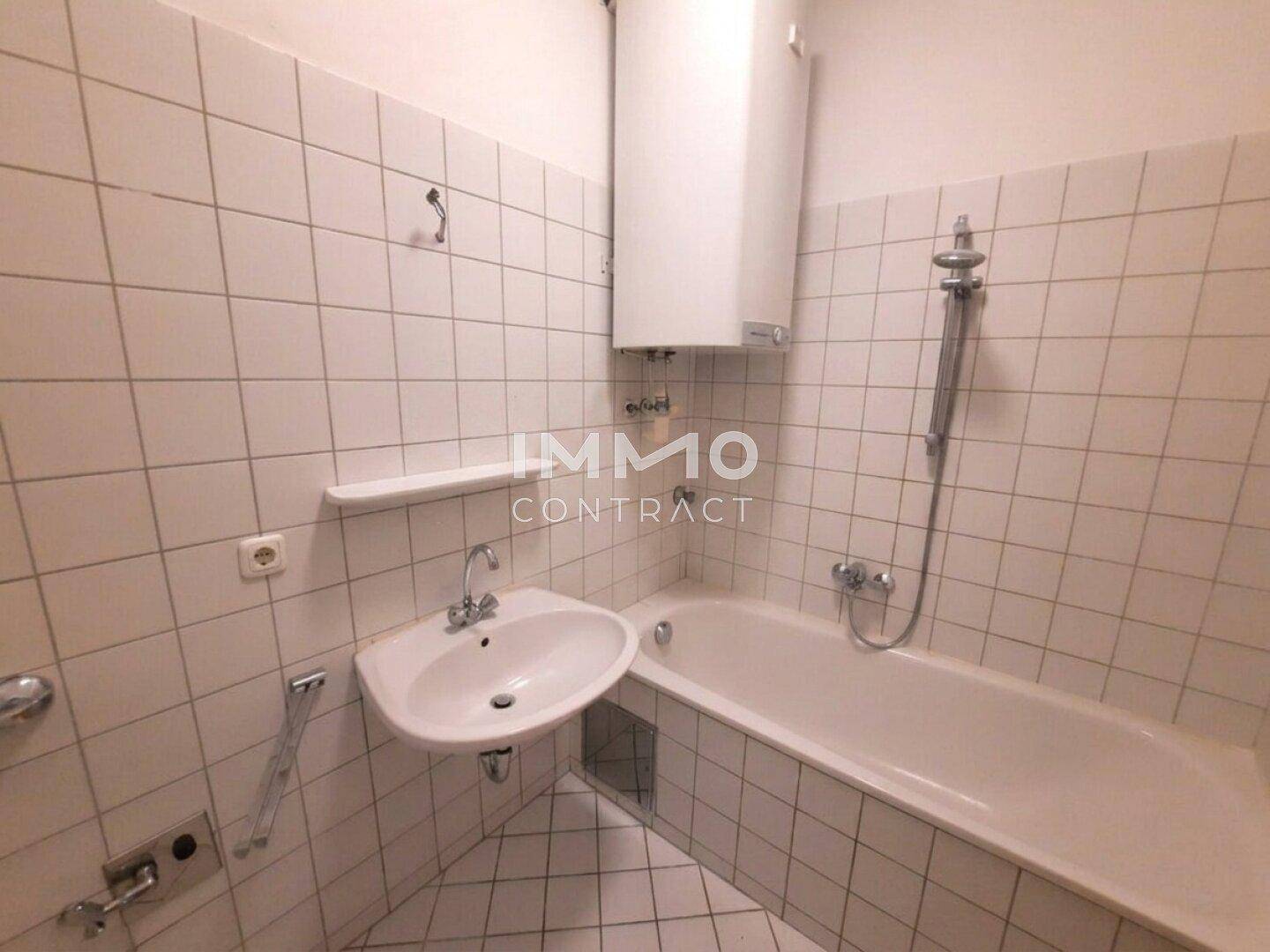 Funktionales Badezimmer mit Badewanne, Waschbecken und weißen Fliesen.