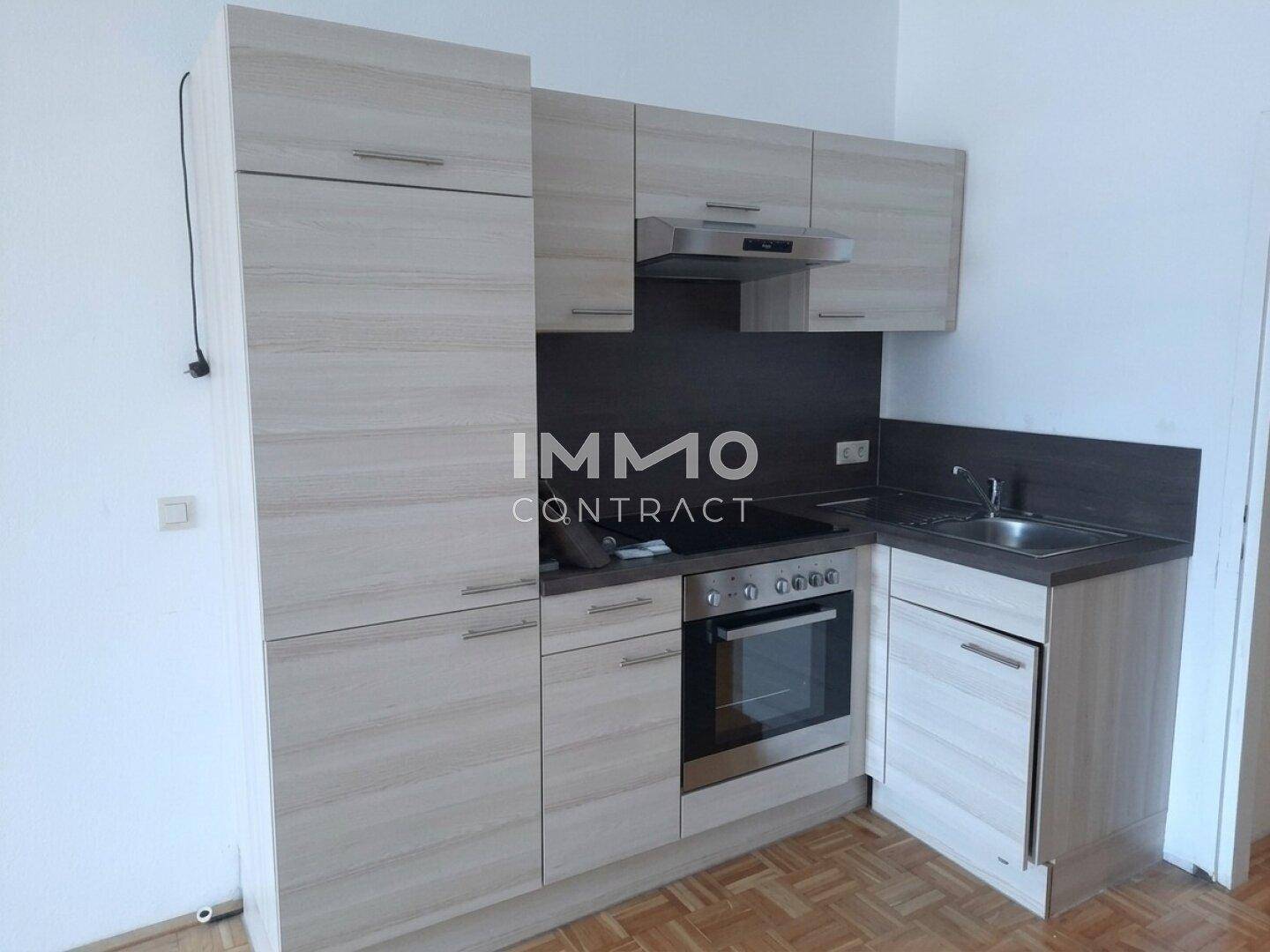 Kompakte Küchenzeile mit hellen Holzfronten, integriertem Backofen und Spüle.