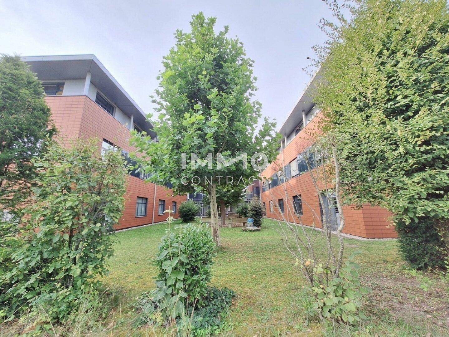 Grüner Innenhof zwischen den Gebäudeteilen mit Bäumen und gepflegten Sträuchern.