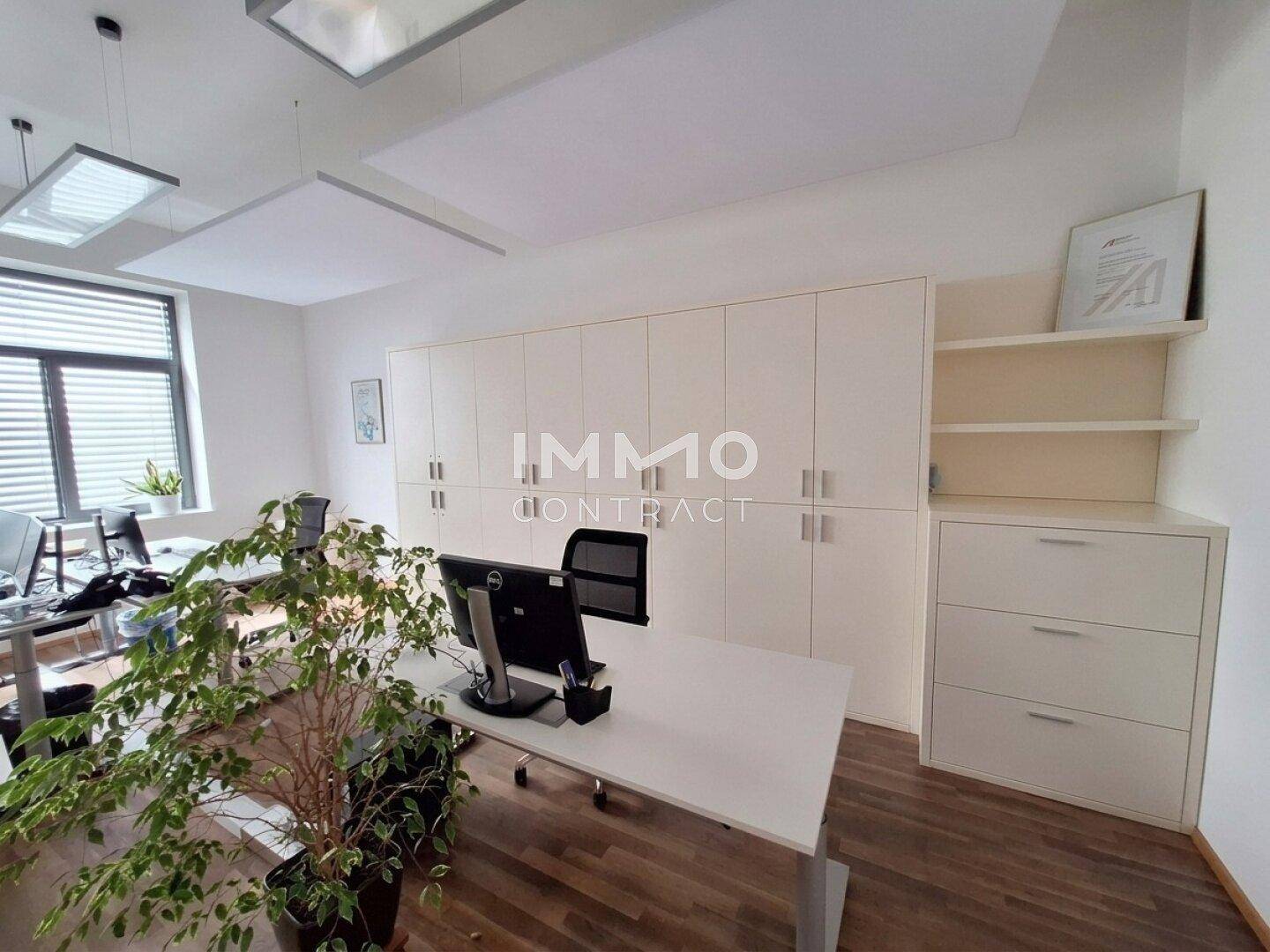 Helles Büro mit modernen Arbeitsplätzen, integrierten weißen Schränken und Holzfußboden.