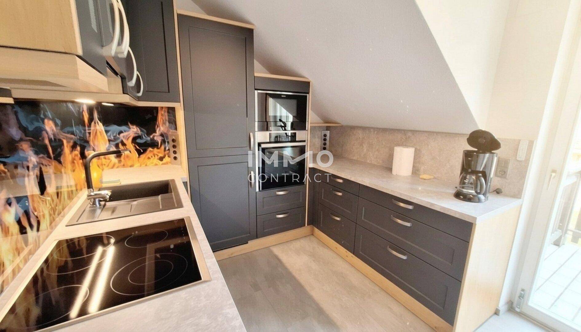 Moderne Küche mit dunkelgrauen Schränken, Einbaugeräten, Induktionskochfeld und Dachschräge.
