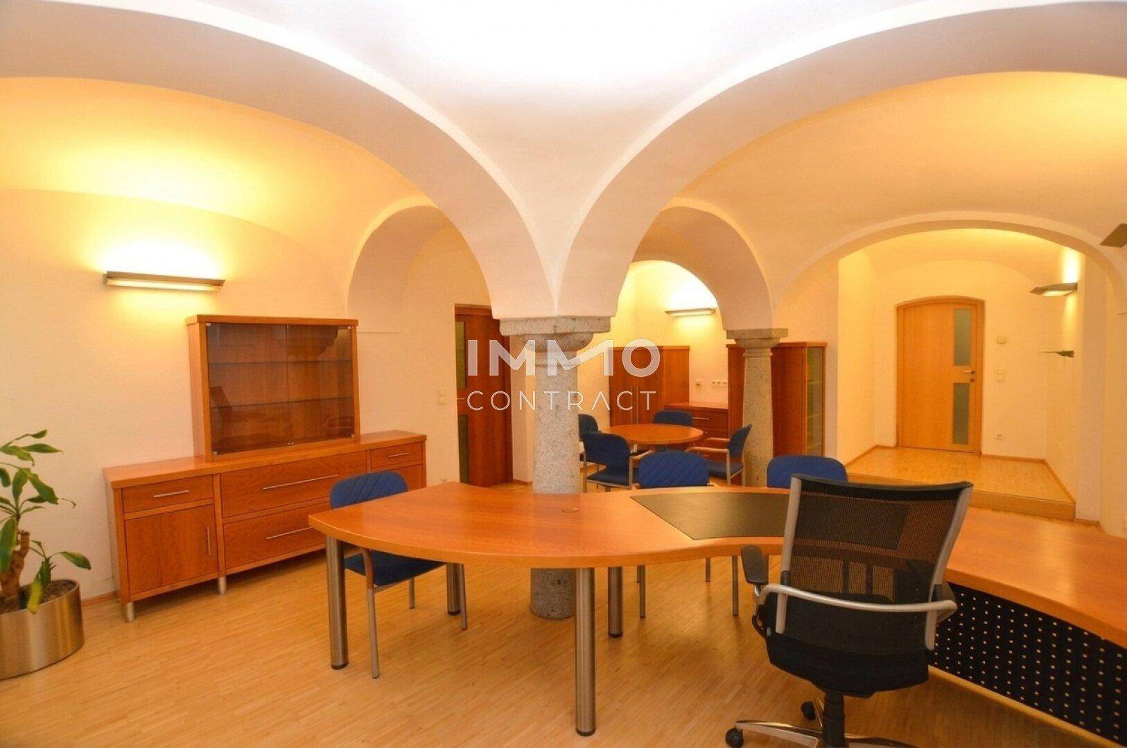 Großes Büro mit beeindruckenden Gewölbedecken und einem steinernen Pfeiler als architektonisches Merkmal.