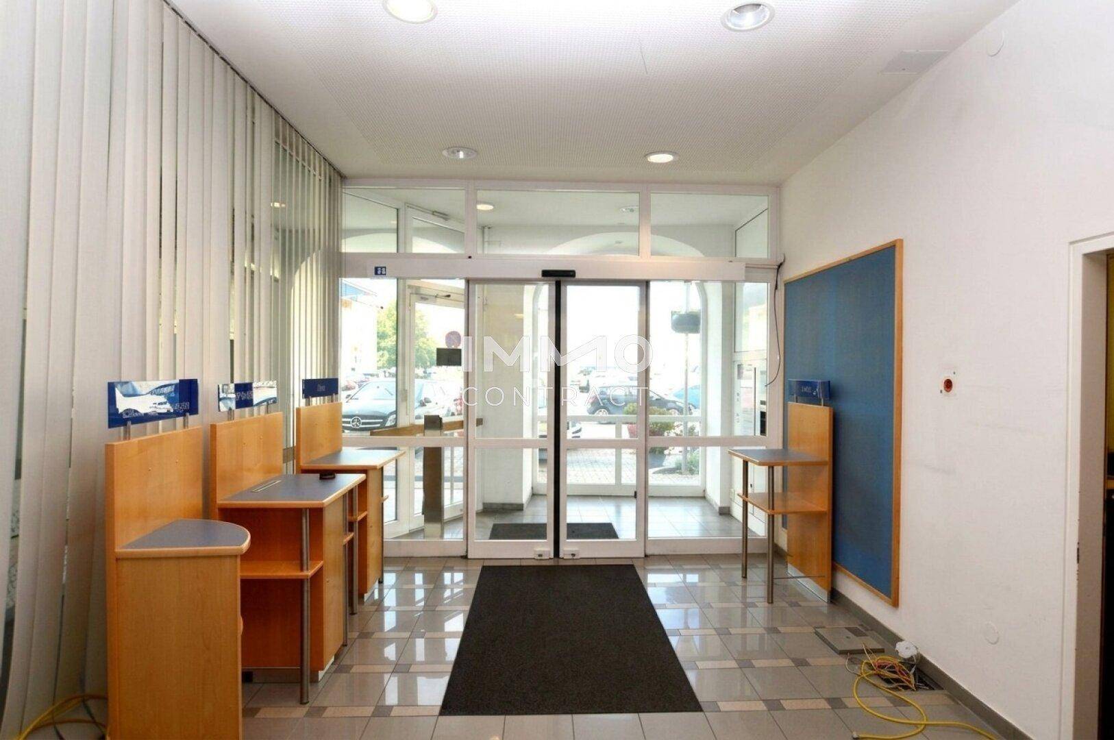 Eingangsbereich mit automatischen Glastüren, Fliesenboden und Informationsständen.