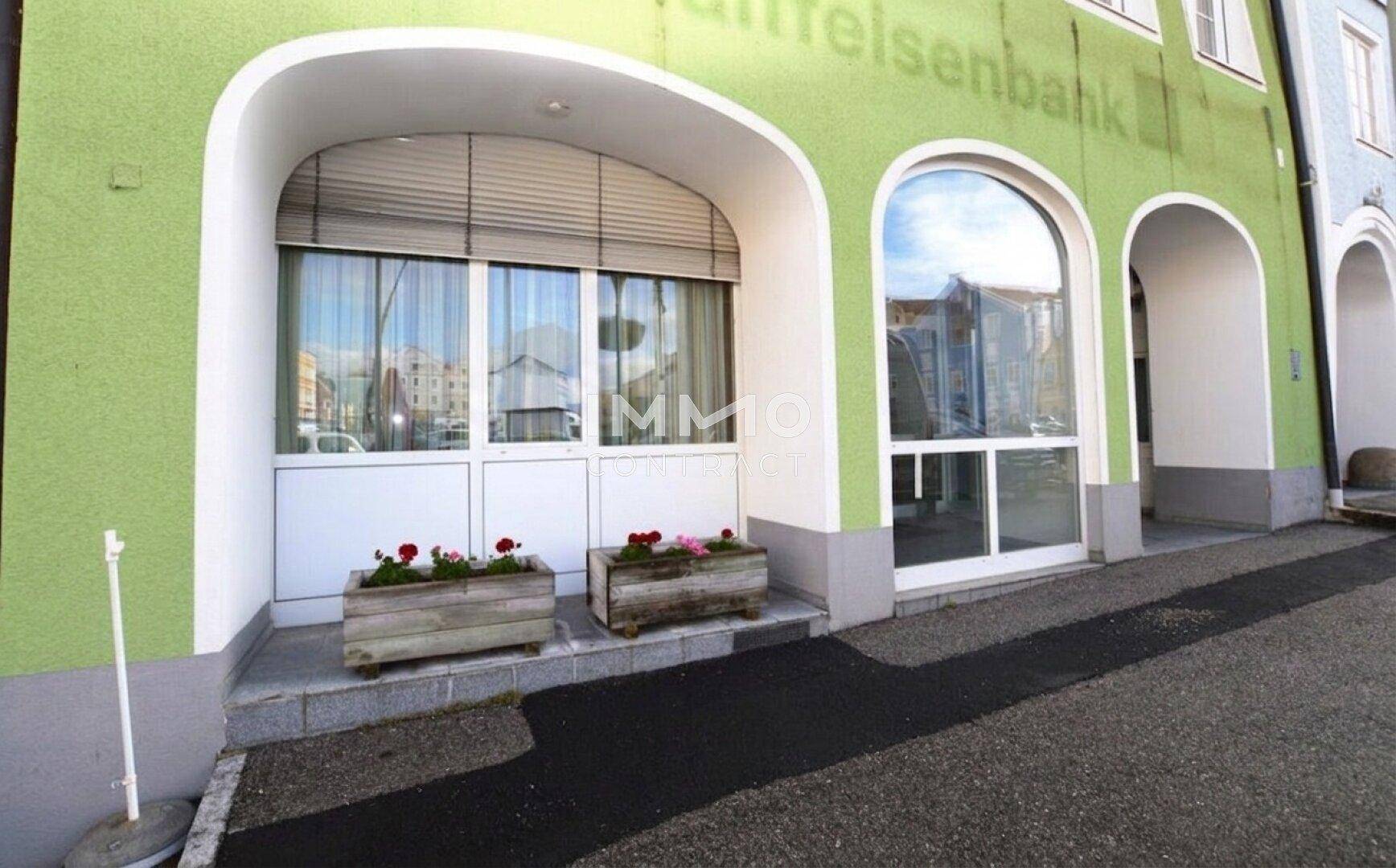 Außenansicht des Gebäudes mit grüner Fassade, Fensterläden und Blumenkästen.