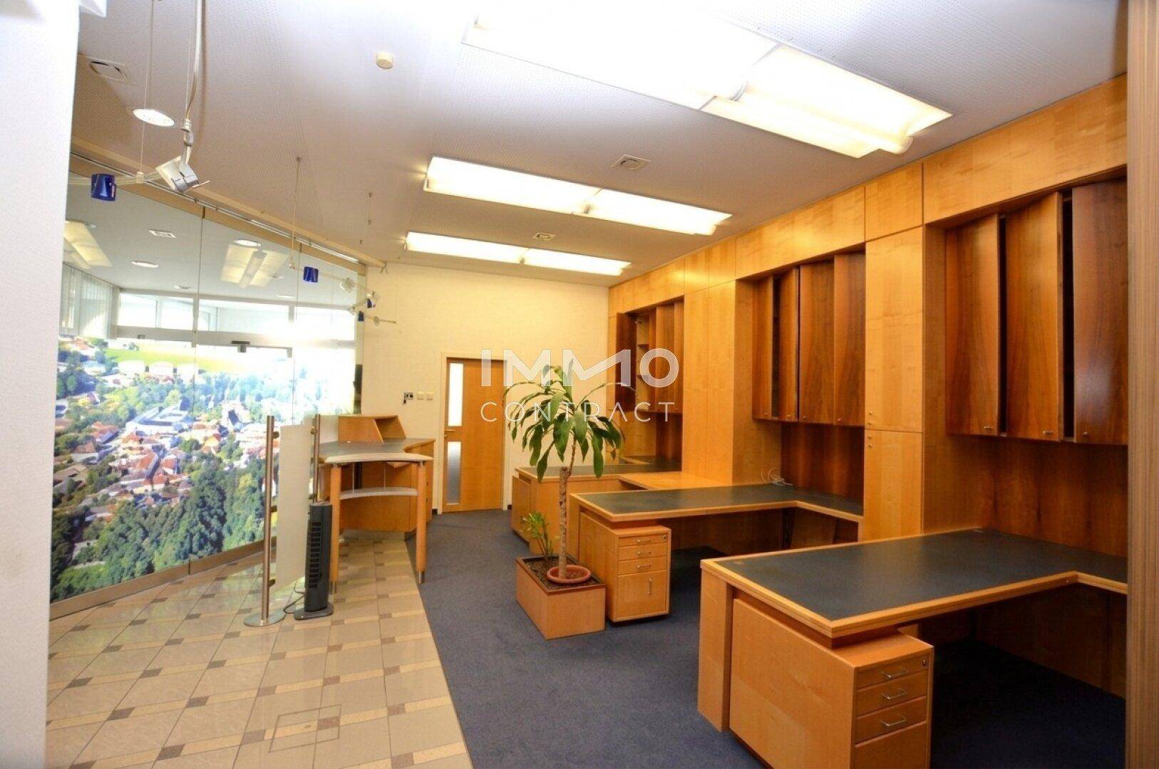 Bürofläche mit umfangreichen Holzregalen, Schreibtischen und Teppichboden.