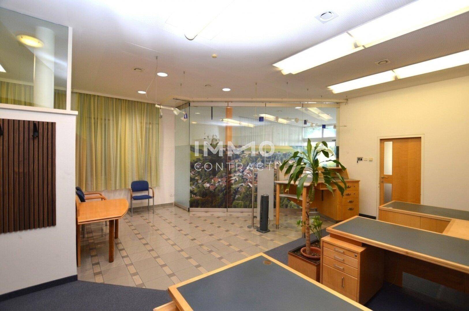 Empfangsbereich oder offenes Büro mit Glaswänden, einer Pflanze und einem Wandbild.