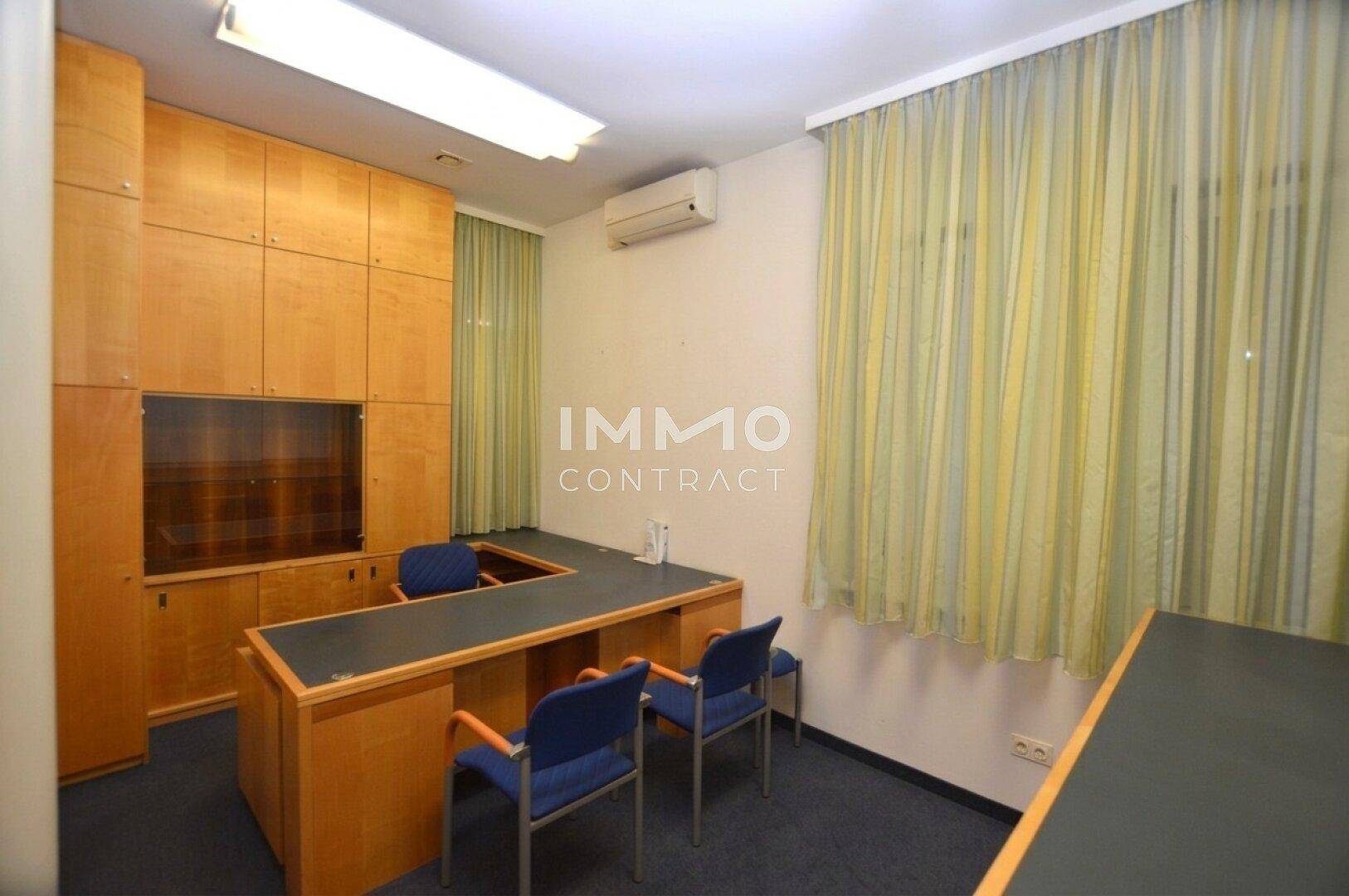 Privates Büro mit Einbauschränken aus Holz, einem Schreibtisch und Klimaanlage.