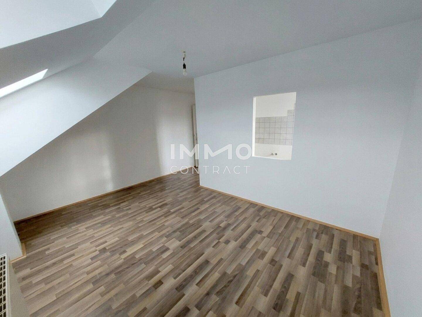 Dachgeschossküche mit Laminatboden, gefliester Wand und schrägen Decken.