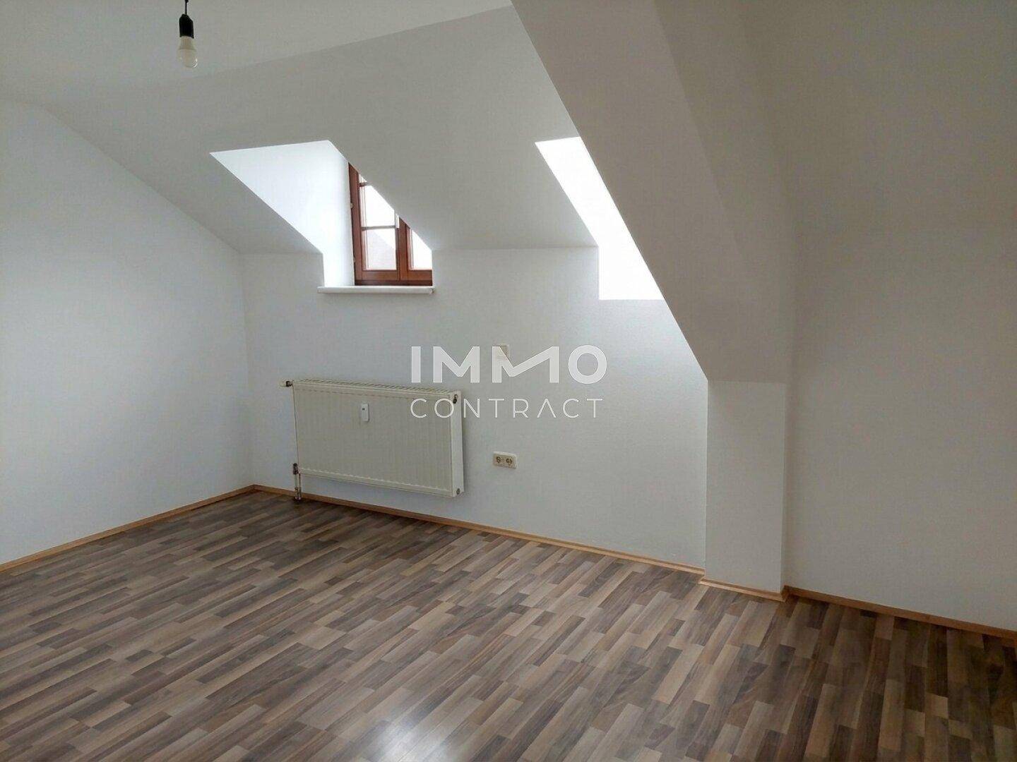 Heller Dachbodenraum mit Laminatboden, schrägen Wänden und Dachfenstern.