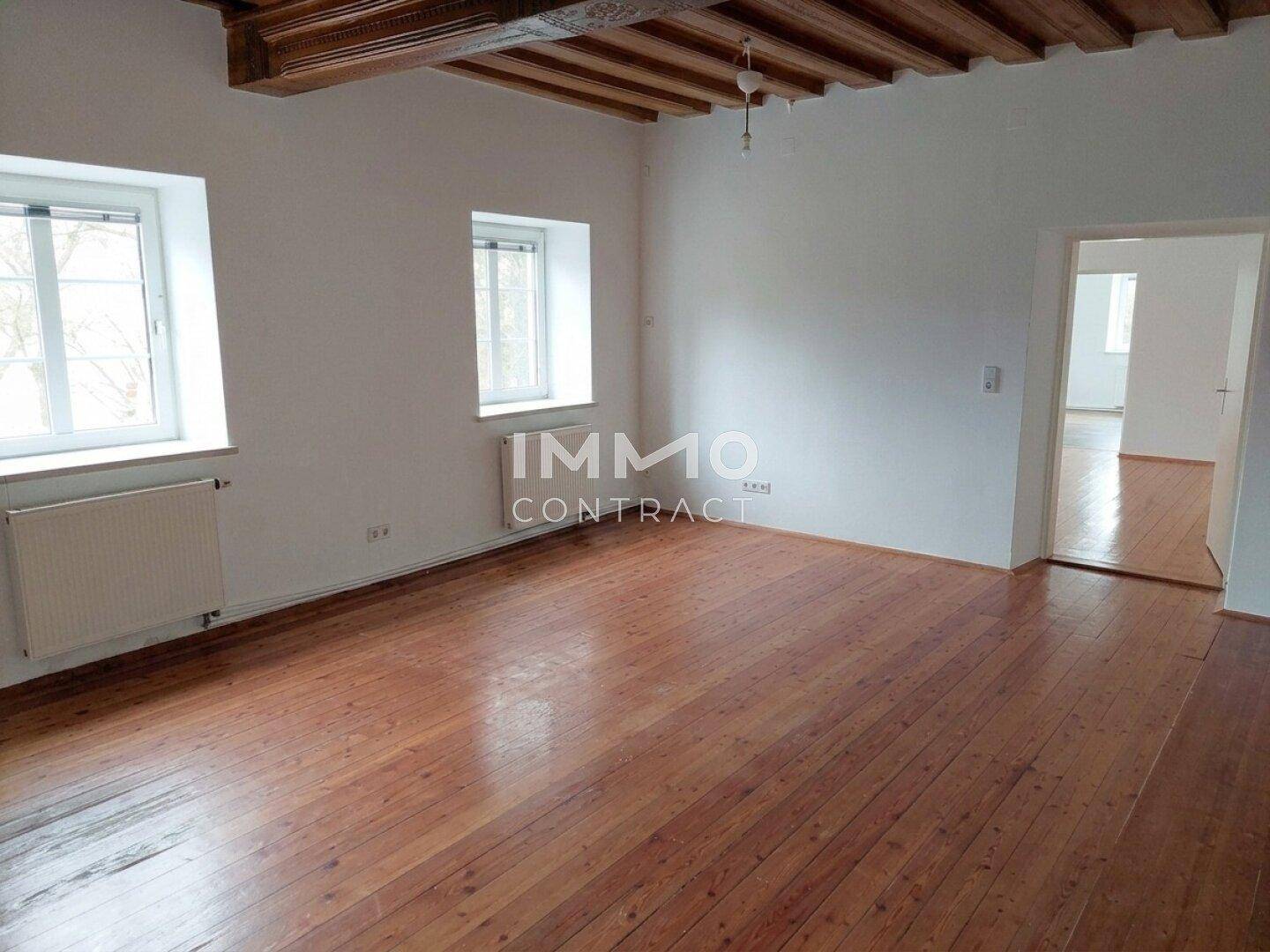 Großes Wohnzimmer mit sichtbaren Holzbalken an der Decke und traditionellem Holzboden.