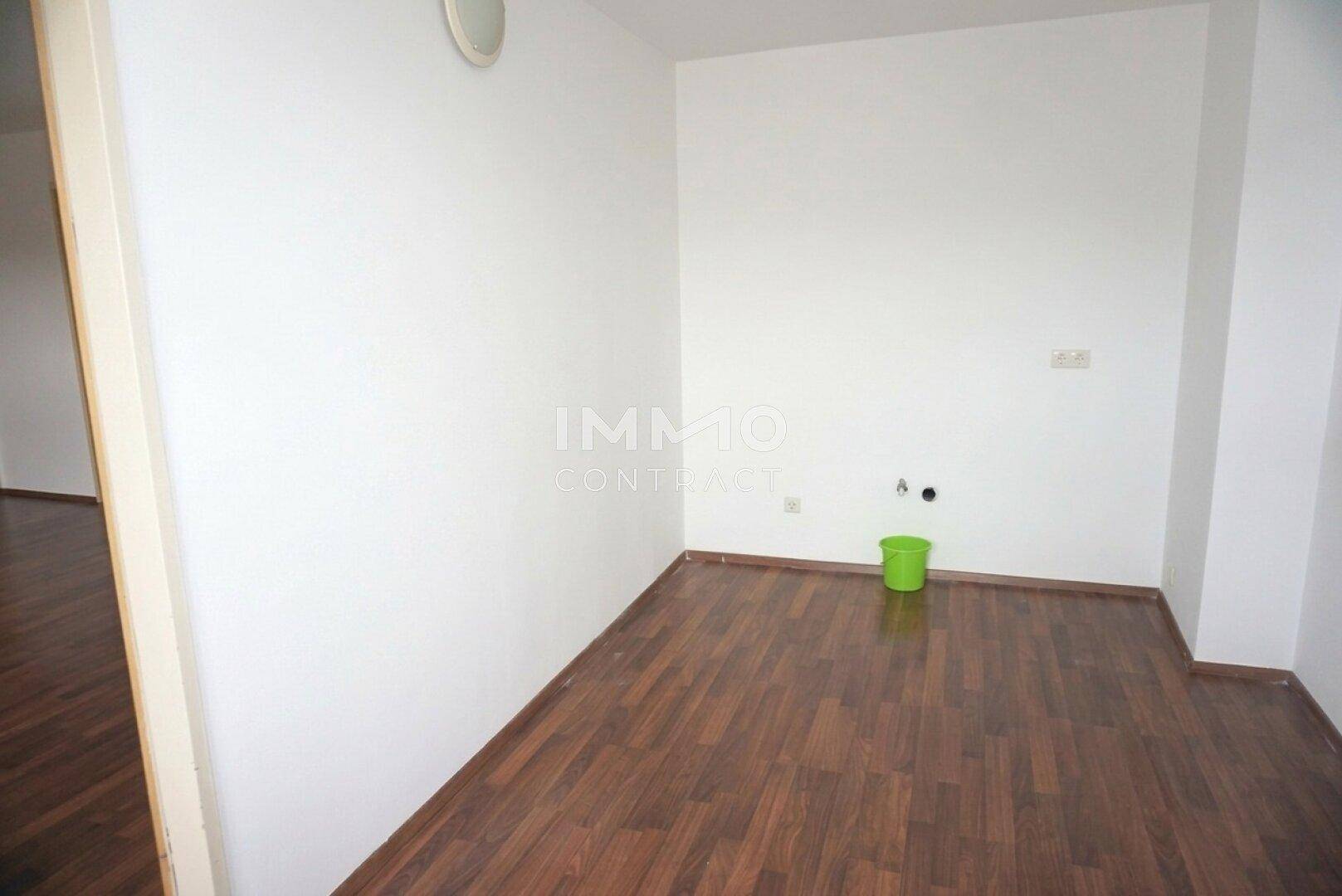 Leerer Raum mit Laminatboden und Anschlüssen, ideal als Hauswirtschaftsraum oder kleine Küche.