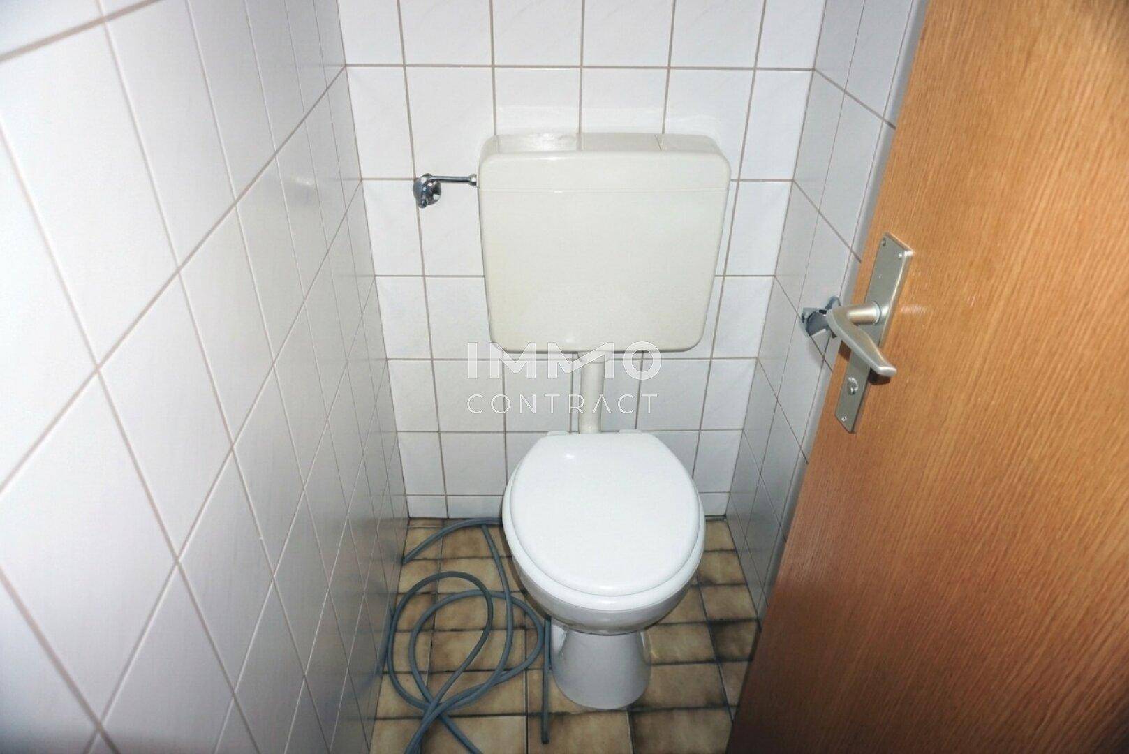 Kleines WC mit weiß gefliesten Wänden und einer Toilette, funktional und sauber.