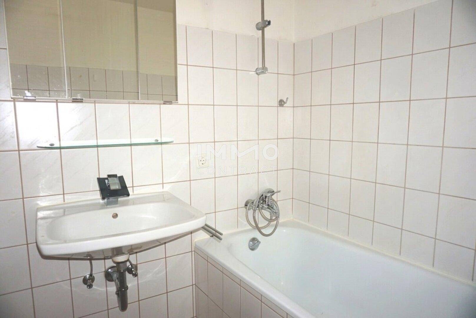 Gefliestes Badezimmer mit Badewanne, Waschbecken und Spiegelschrank, in gutem Zustand.