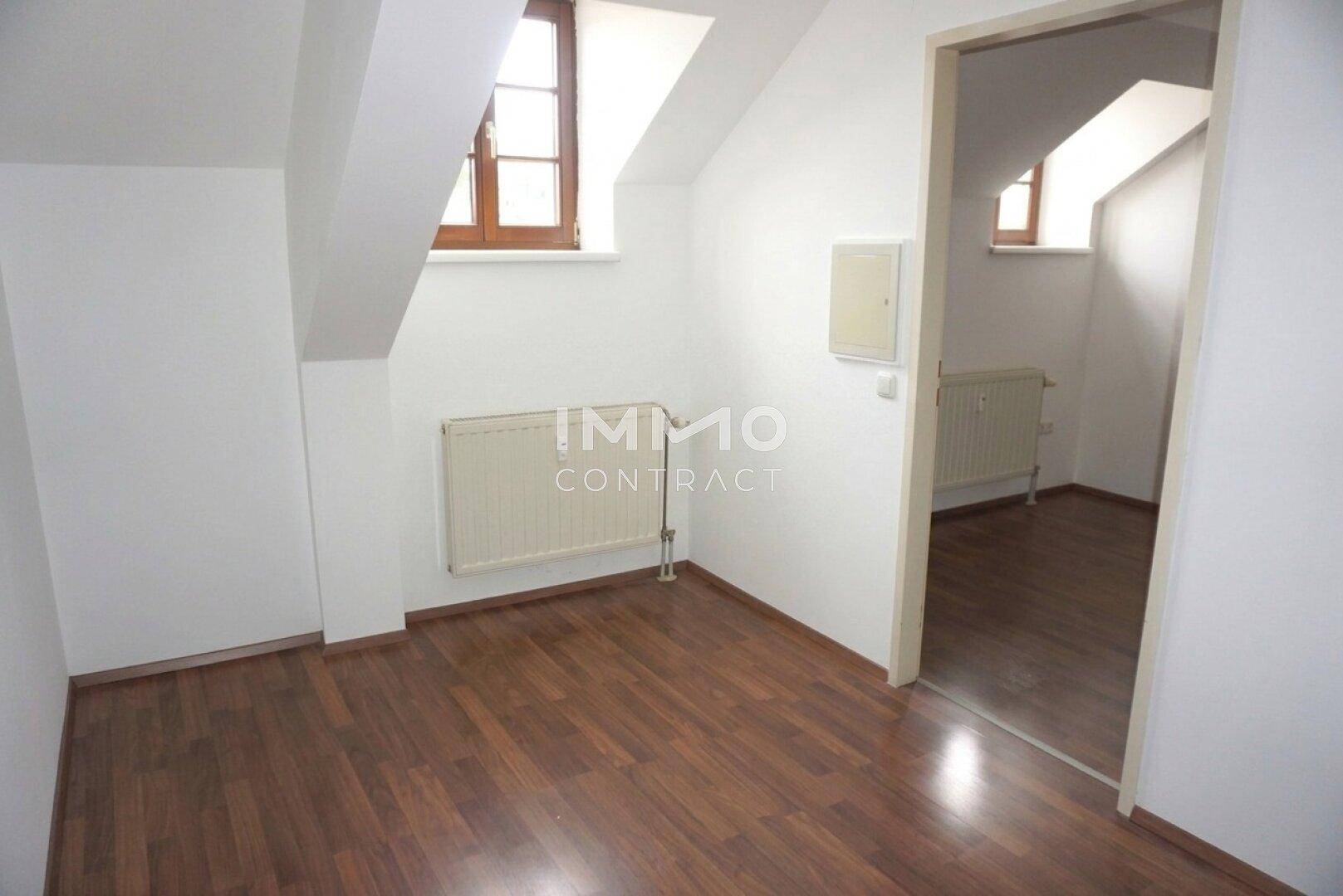 Gemütliches Schlafzimmer im Dachgeschoss mit Laminatboden, Dachgaubenfenster und Heizkörper.