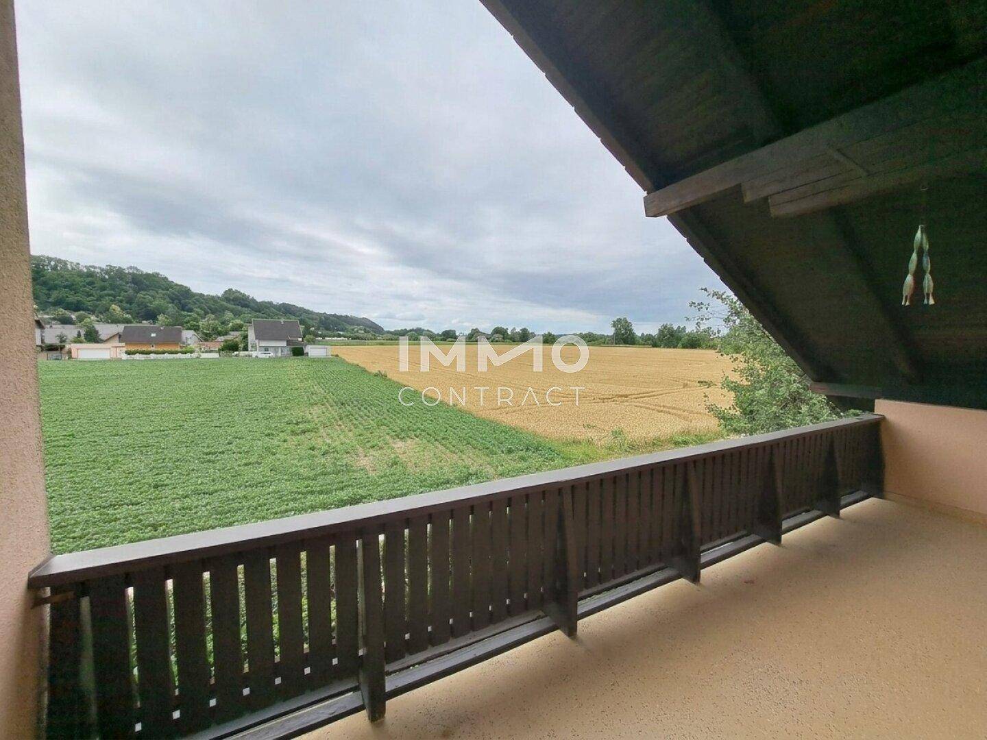 Balkon mit Holzgeländer und einem weiten, unverbauten Blick auf die angrenzenden Felder und Hügel.