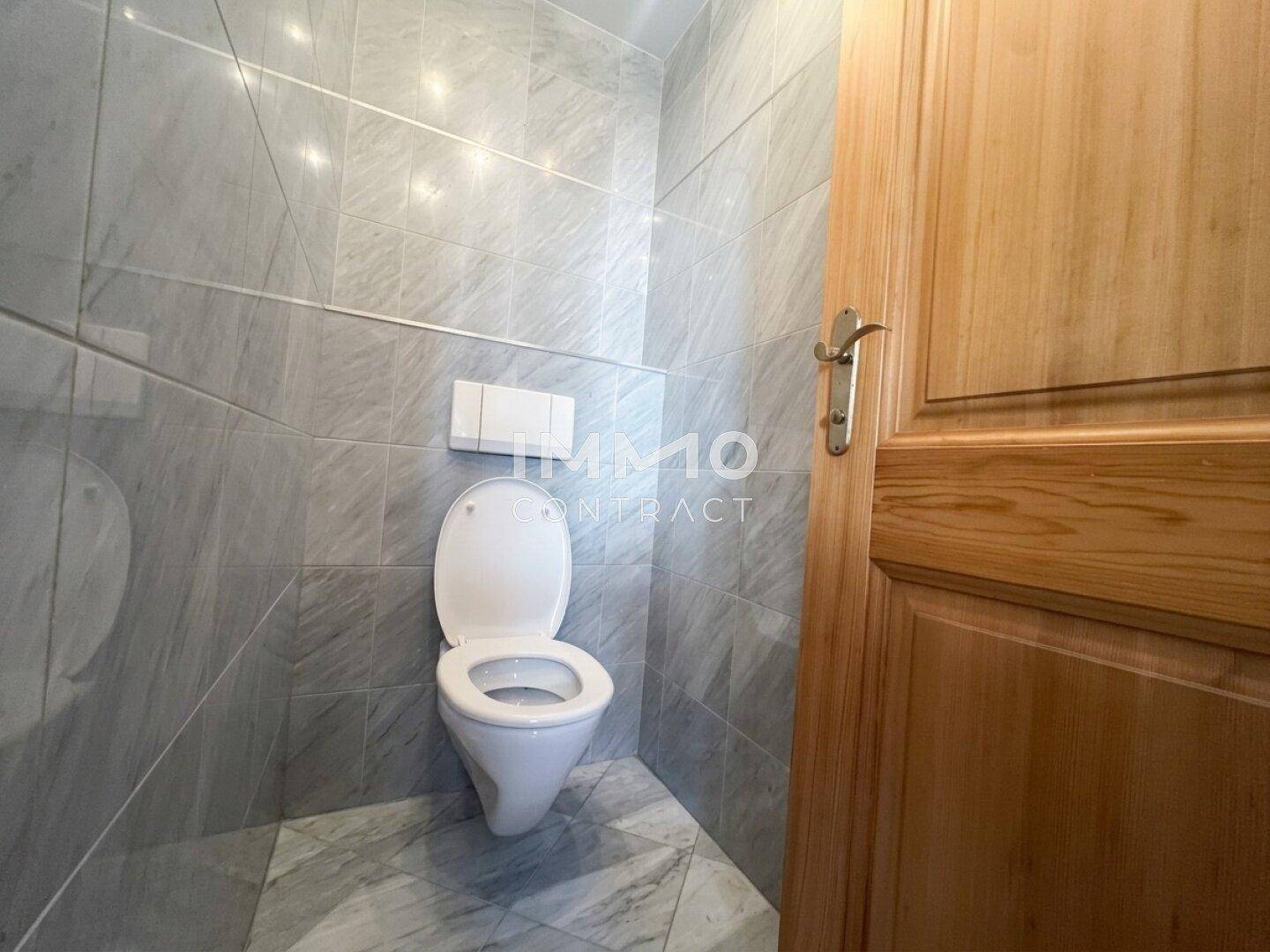 Separates WC mit wandhängender Toilette und grauen Marmorfliesen, sauber und funktional.