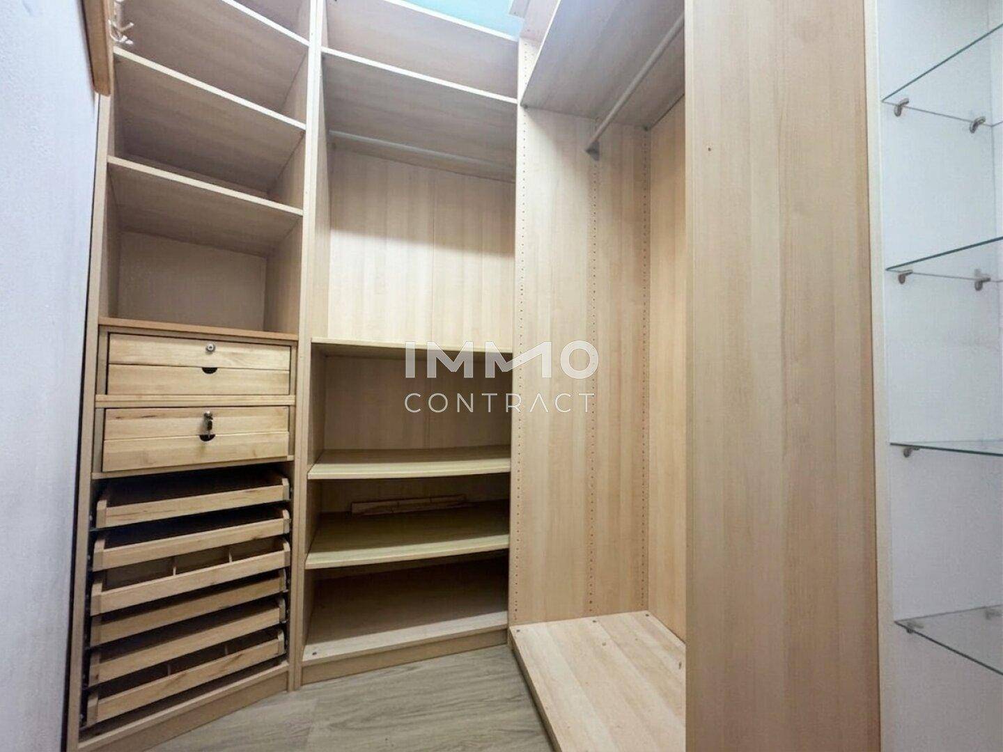 Begehbarer Kleiderschrank mit Holzregalen und Schubladen für organisierte Aufbewahrung von Kleidung.