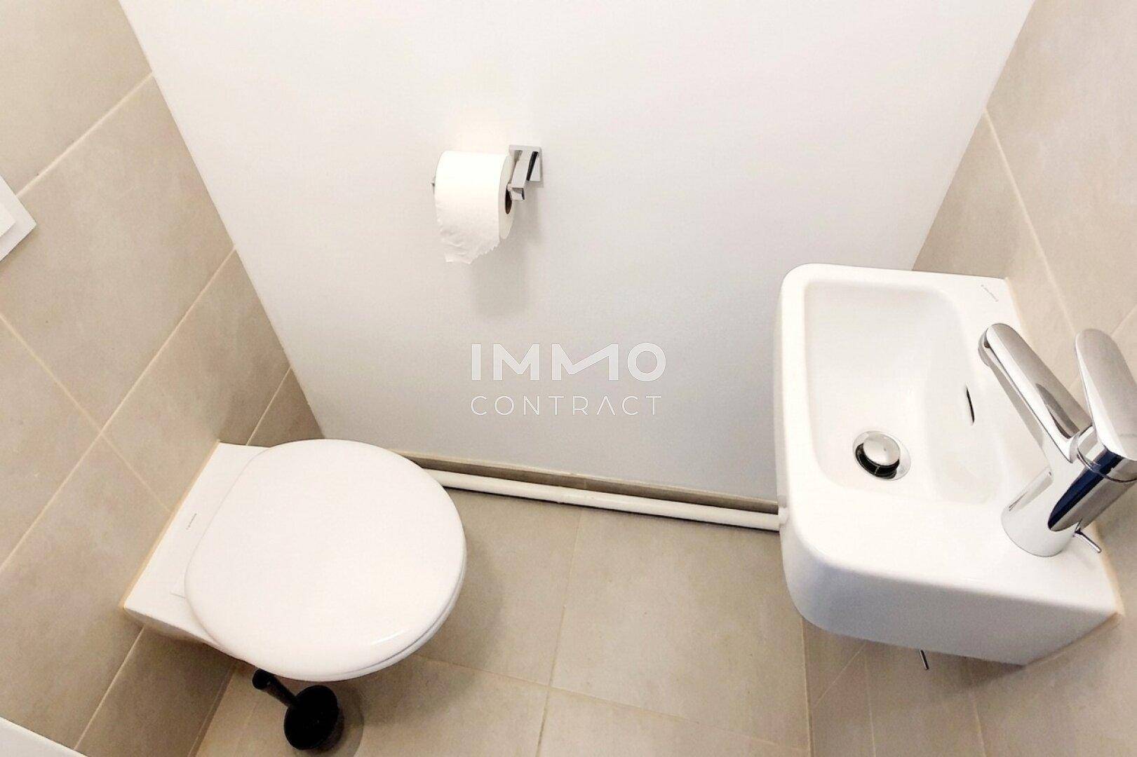 Modernes Gäste-WC mit wandhängender Toilette, kleinem Waschbecken und hellen Fliesen.