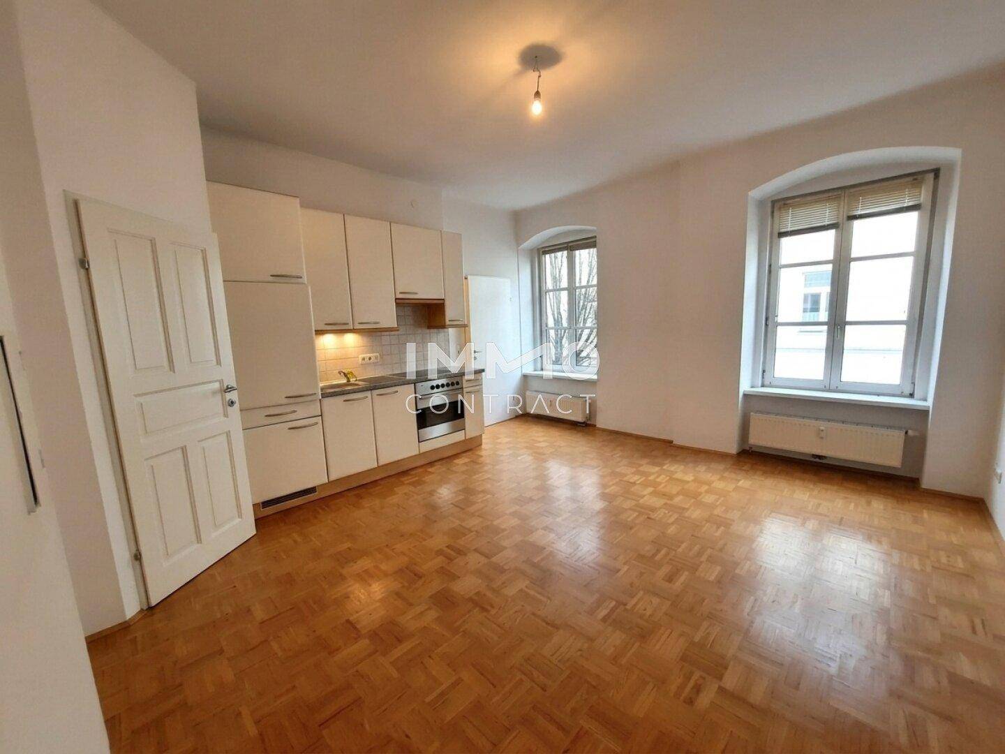 Geräumiges Wohn-Esszimmer mit Parkettboden und integrierter Küchenzeile, bereit zur Einrichtung.
