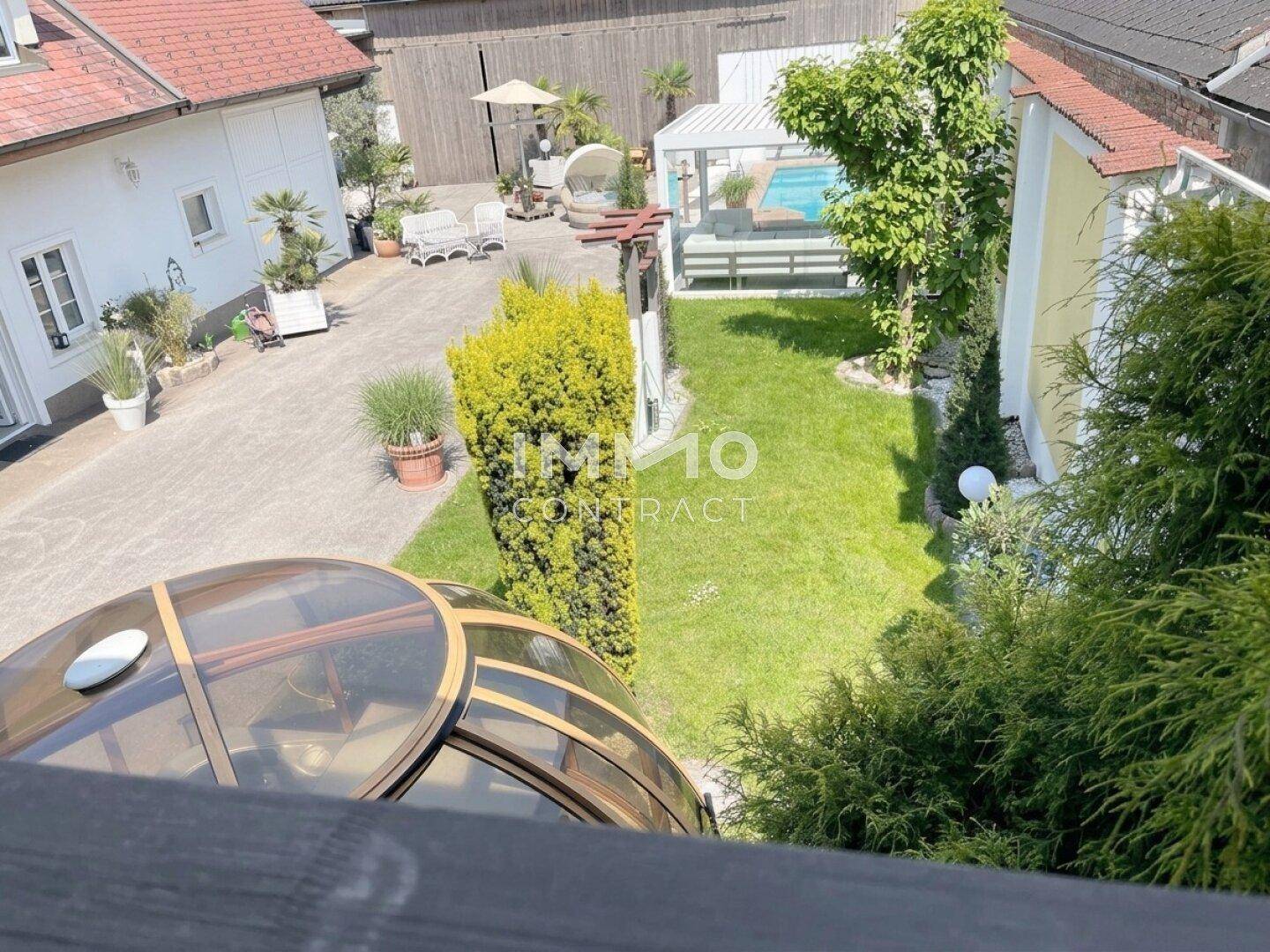 Weitläufige Gartenanlage mit Rasenfläche, Poolbereich und verschiedenen Sitzgelegenheiten unter freiem Himmel.