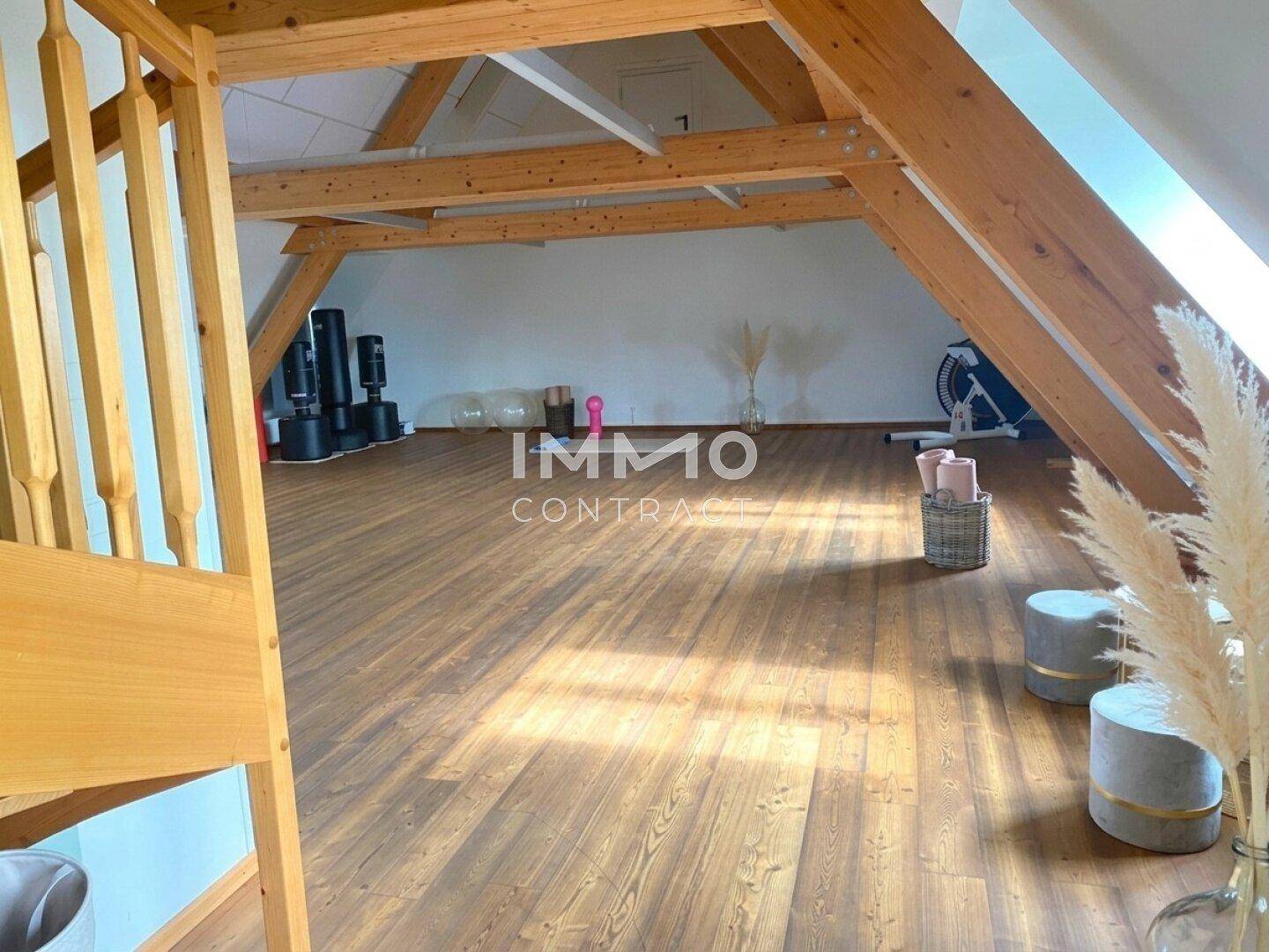 Geräumiger Dachbodenraum mit sichtbaren Holzbalken und Holzboden, ideal für Sport oder Hobby.