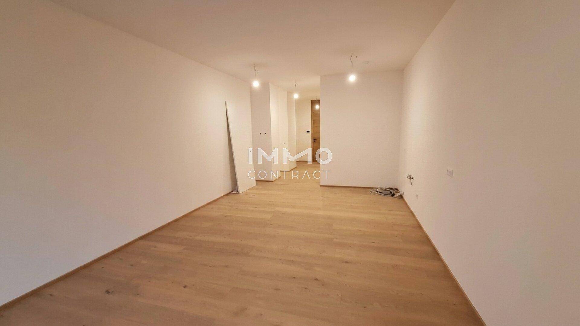 Heller, leerer Raum mit modernem Holzfußboden und weißen Wänden, bereit zum Einzug.