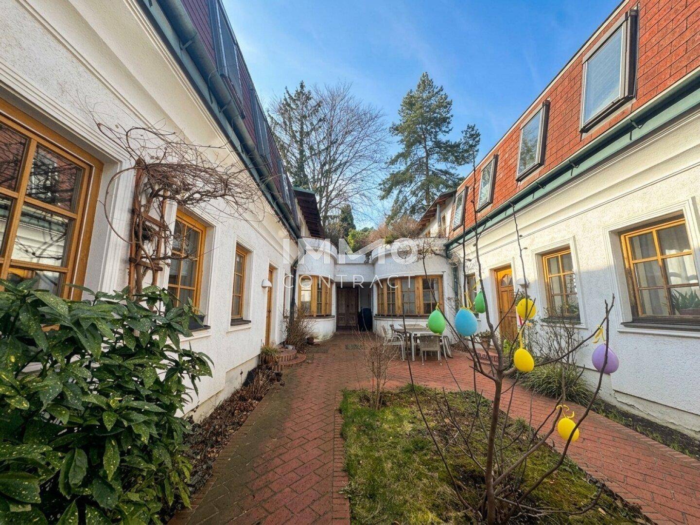 Malerischer Innenhof mit gepflastertem Weg, frühlingshafter Dekoration und Gebäudefassaden.