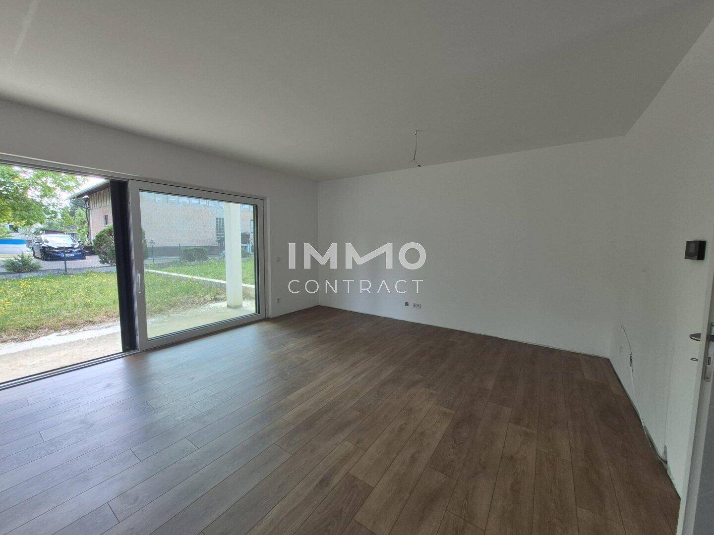 Heller Wohnbereich mit Laminatboden und großer Schiebetür, die viel Tageslicht hereinlässt.