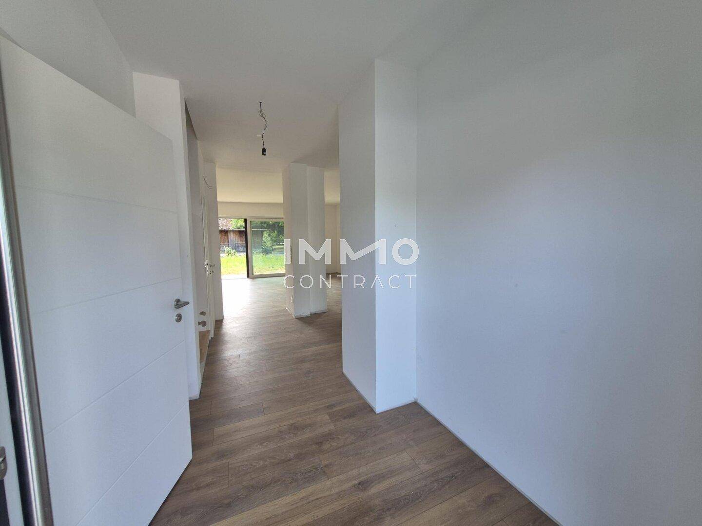 Heller Flur mit modernem Laminatboden und Zugang zu weiteren Räumen mit viel Tageslicht.