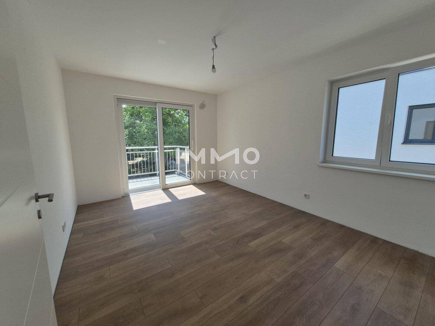 Schlafzimmer mit Laminatboden und direktem Zugang zu einem Balkon, der viel Licht spendet.