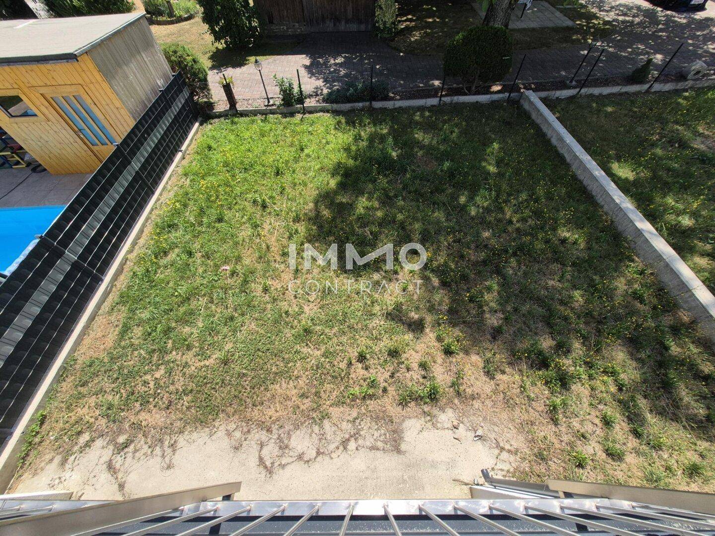 Kleiner Gartenbereich mit Rasenfläche, angrenzendem Holzschuppen und einem Pool.