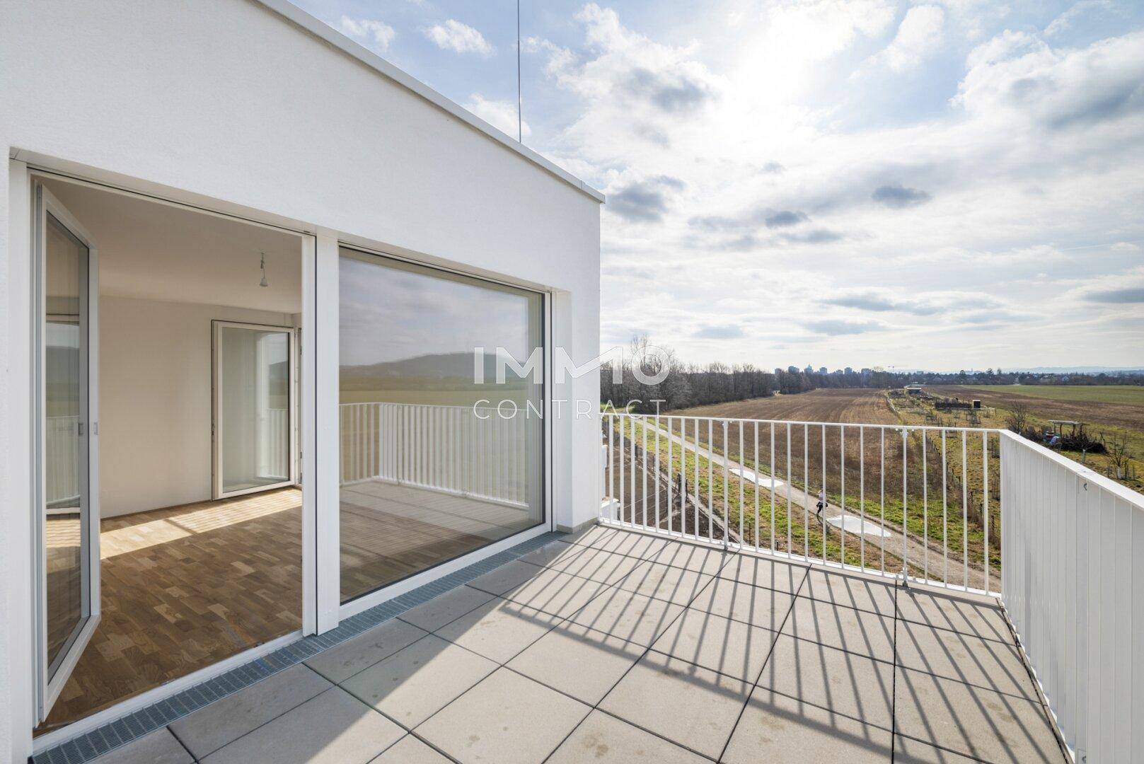 Geräumiger, sonniger Balkon mit Fliesenboden und großen Fenstern, die einen weiten Blick bieten.