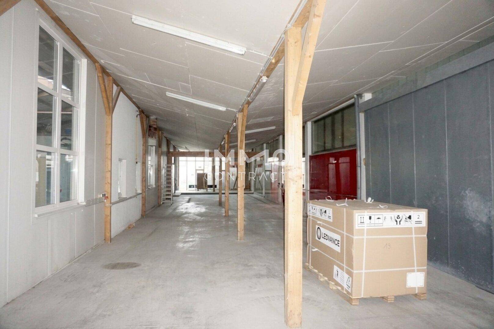 Langer Flur oder Lagerbereich mit Holzbalken und Fenstern, der zusätzlichen Platz für Materialien bietet.