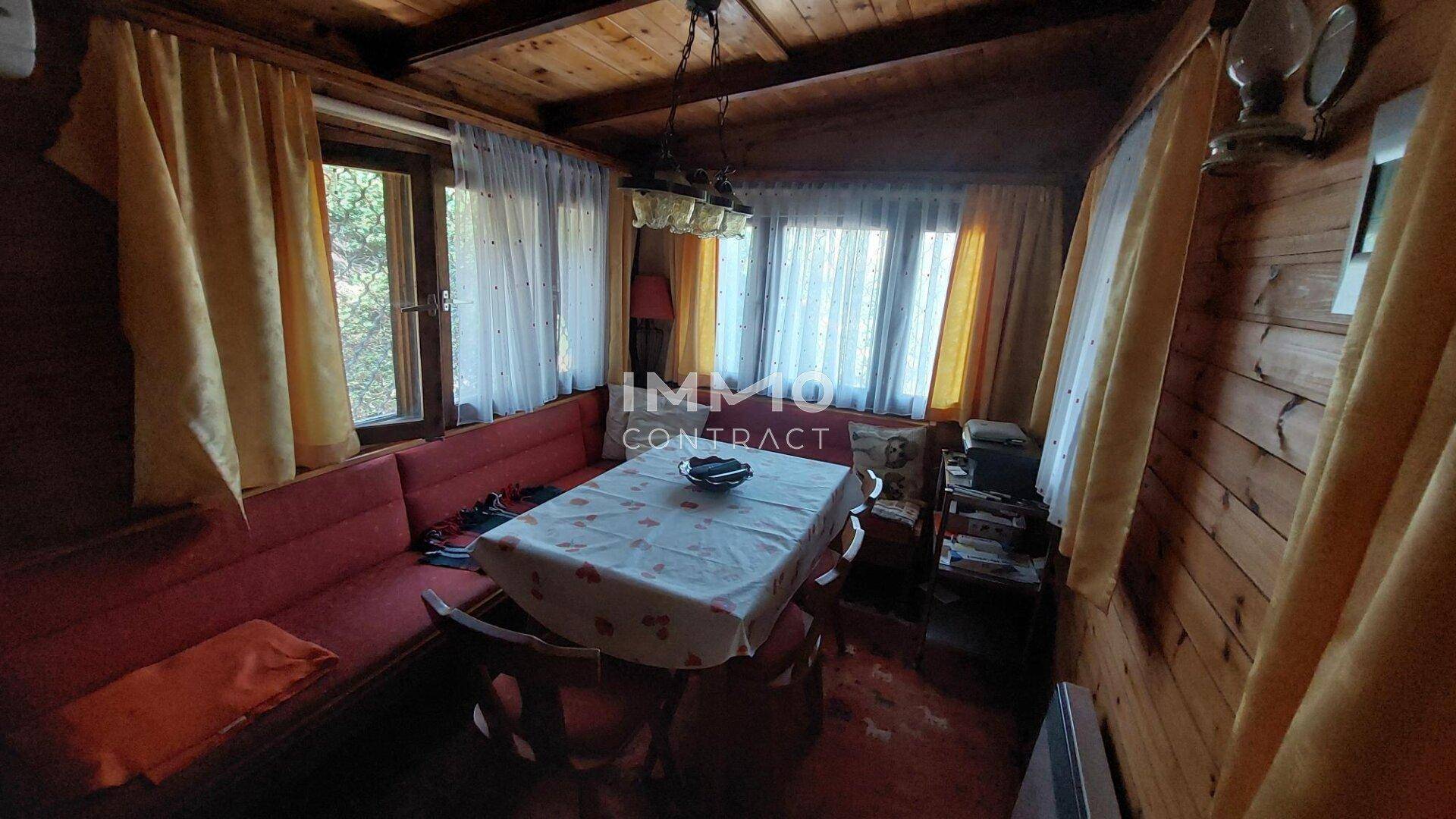 Rustikaler Wohn-Essbereich mit Holzwänden, Holzdecke und einer gemütlichen Sitzecke mit Esstisch.