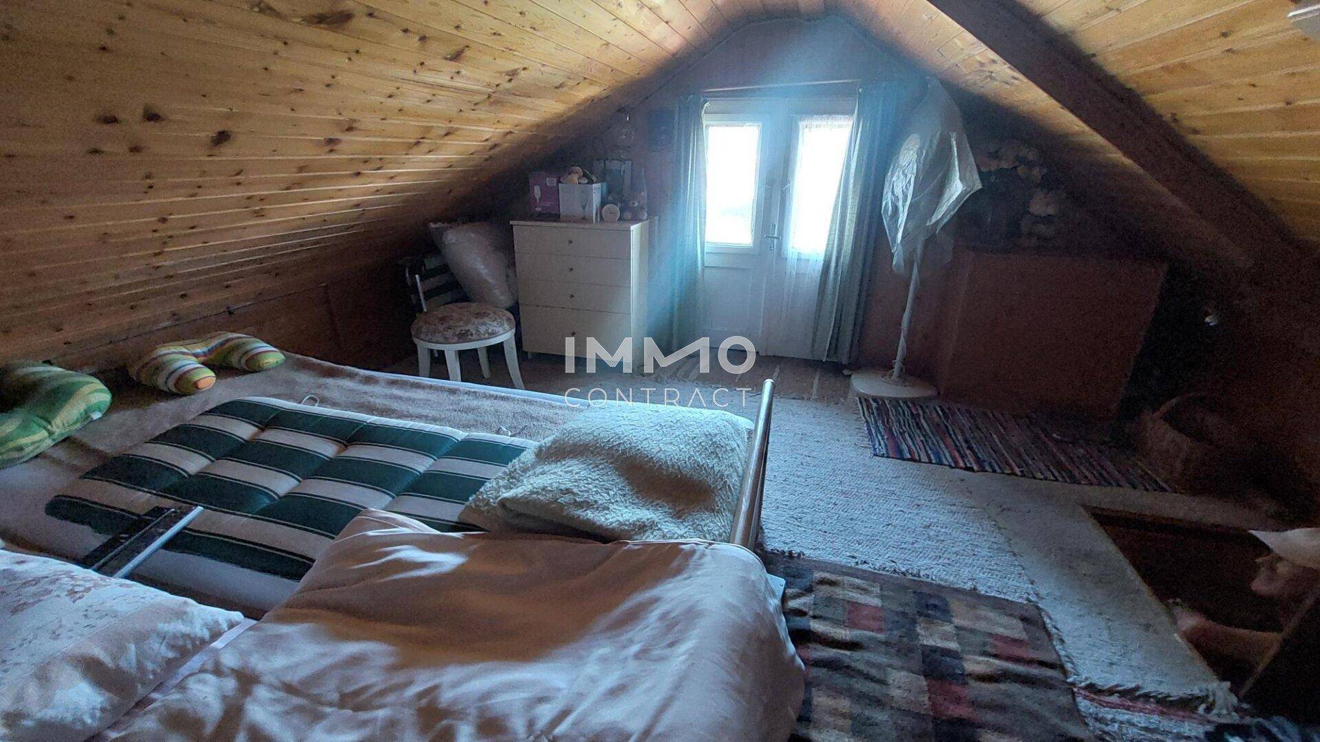 Dachgeschoss-Schlafzimmer mit gemütlichem Bett, Fenster und charakteristischen schrägen Holzdecken.