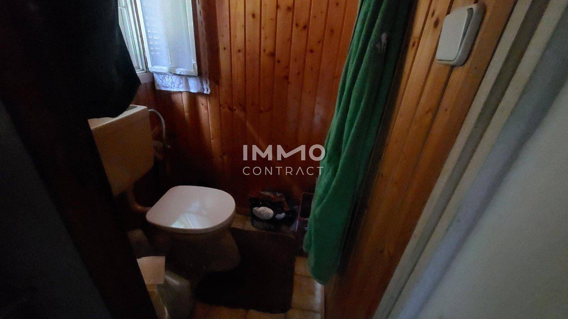 Kleines WC mit Holzvertäfelung an den Wänden und einer einfachen Toilette.